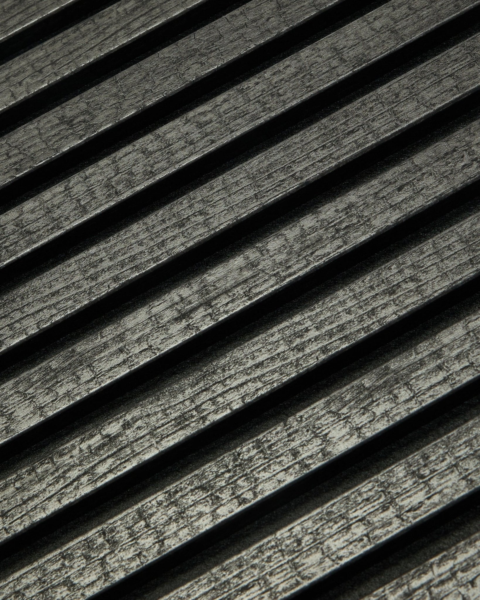 Primo piano di WoodUpp Rebel Akupanel in Charcoal (240x60 cm) che mostra black, doghe acustiche scanalate disposte in diagonale per un migliore assorbimento del suono.