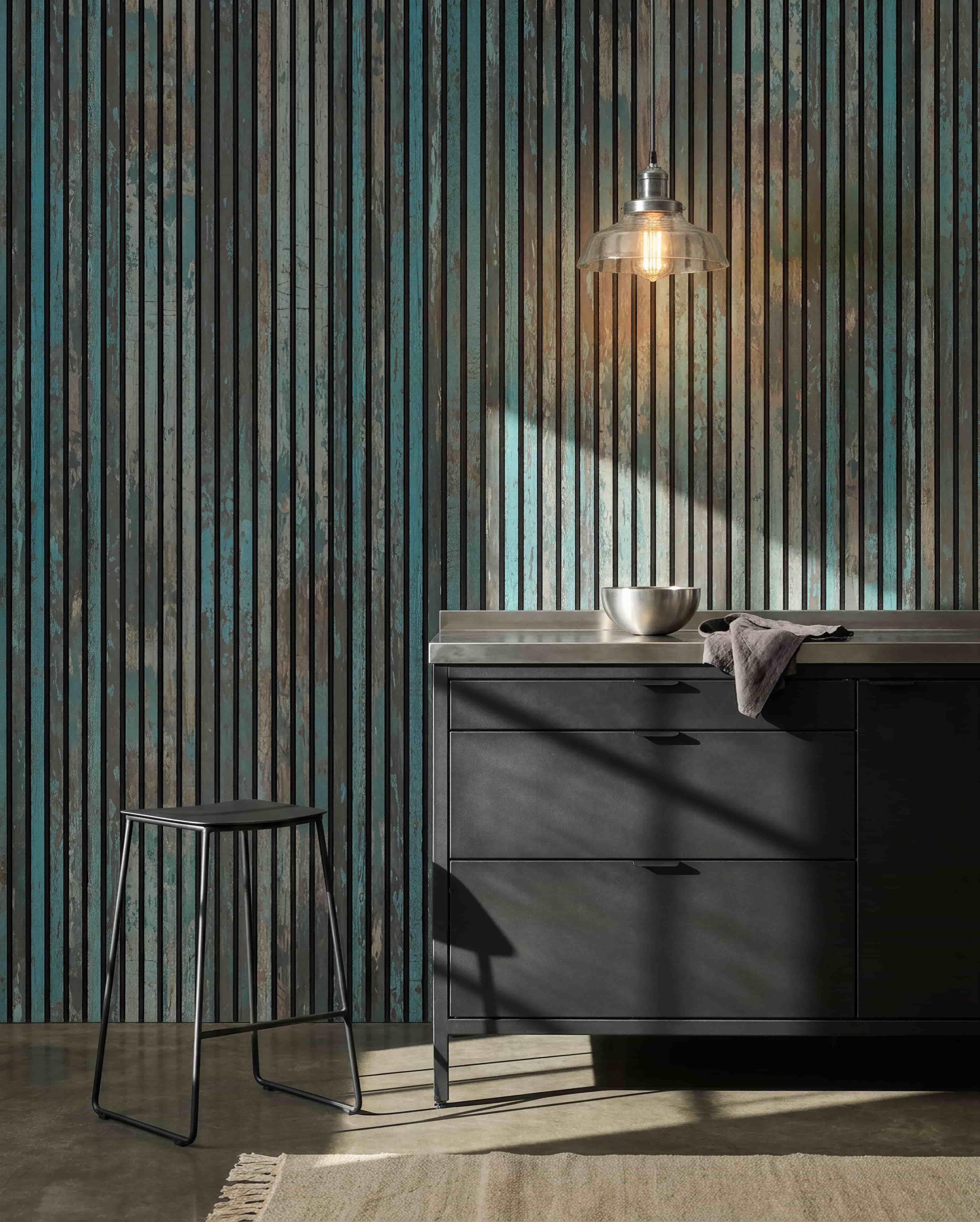 Cucina moderna con sgabelli black, mobili black, una ciotola sotto una lampadina e un Pannello acustico WoodUpp Akupanel Oxide Blue sulla parete per un maggiore comfort acustico.