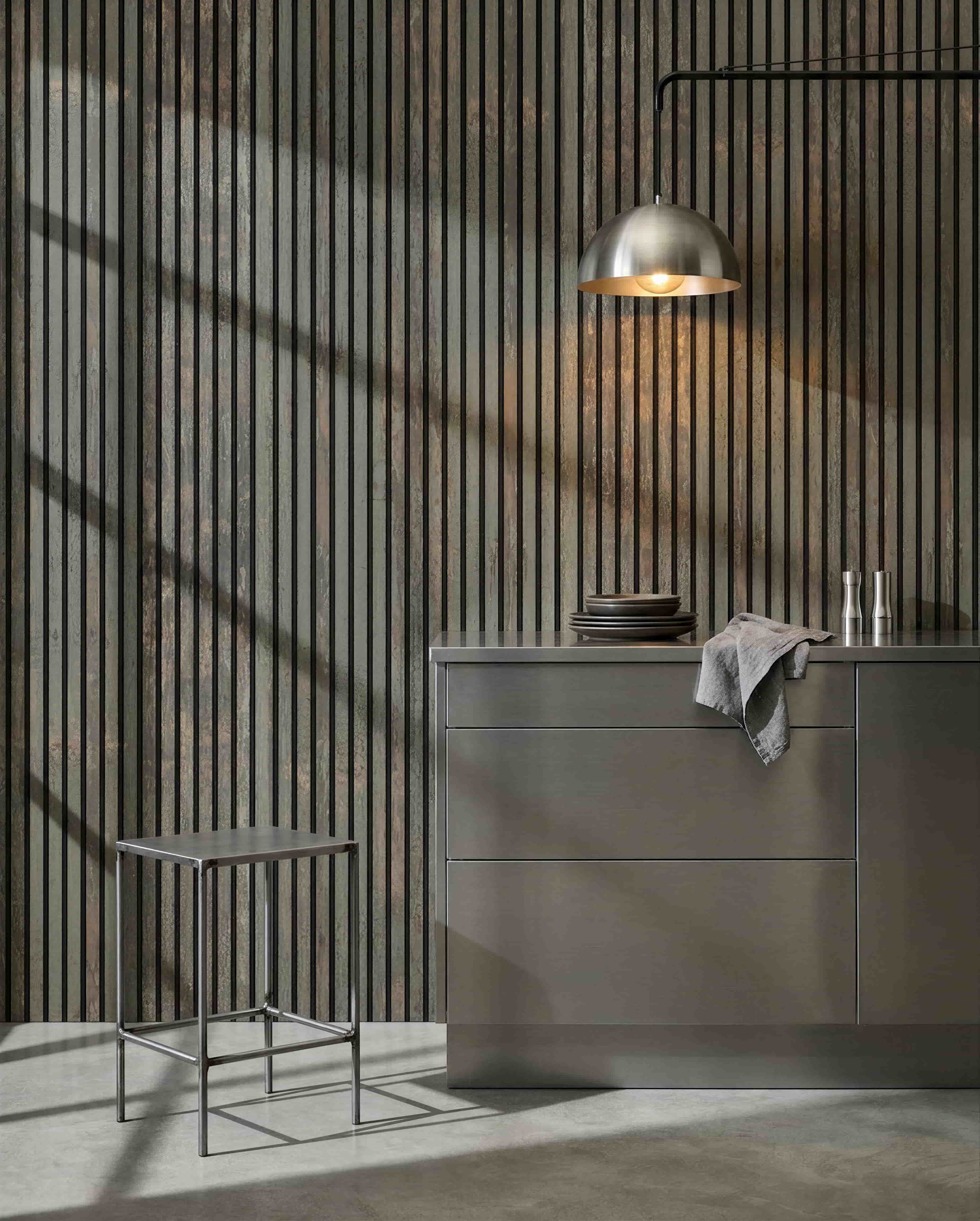 Cucina minimalista con sgabello in metallo, isola grey e stoviglie, con un pannello acustico in legno WoodUpp Akupanel in Oxide Grey/Black Felt per il controllo del suono.