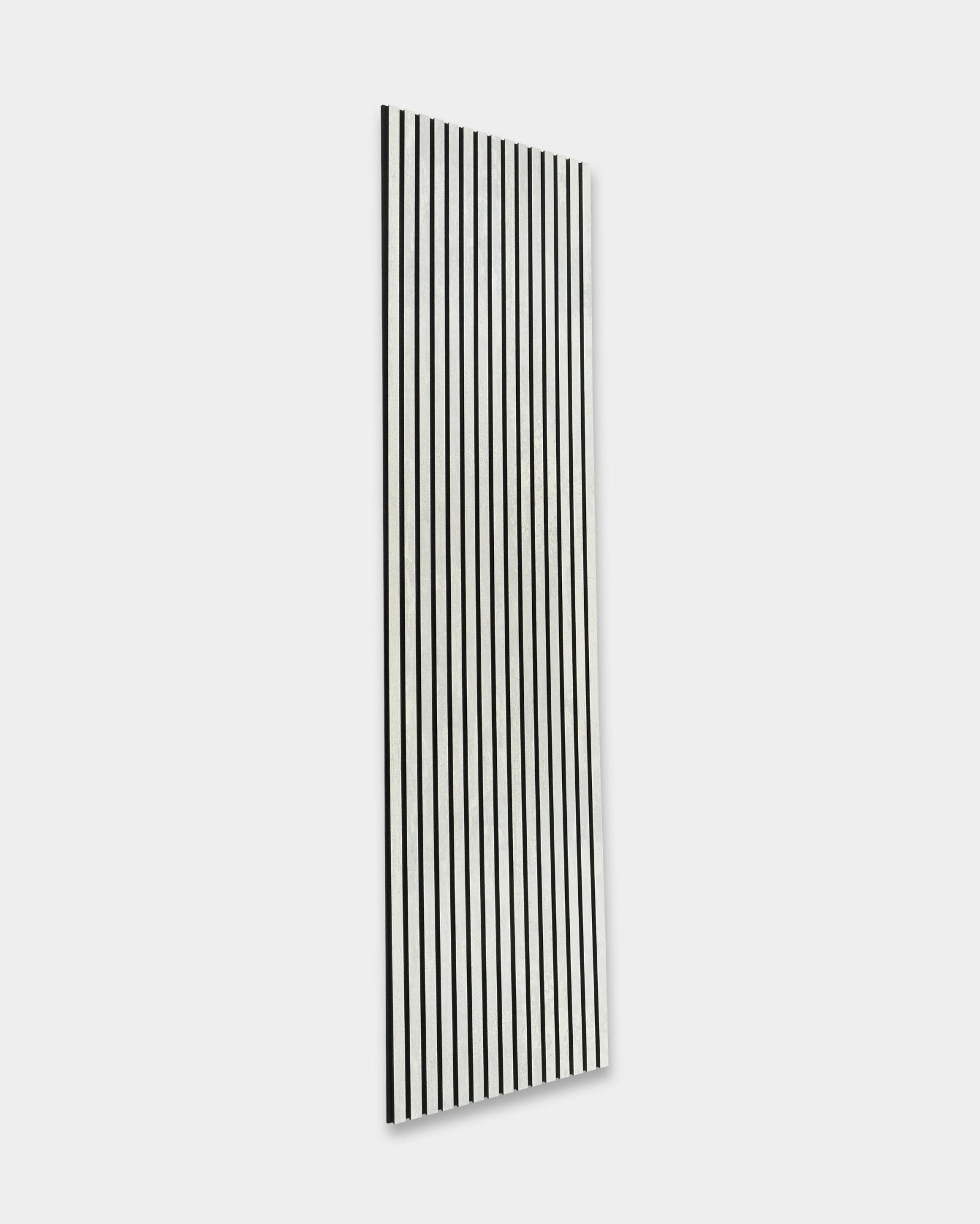 WoodUpp Rebel Akupanel in Oxide White (240 x 60 cm) con lamelle black vertical, che migliorano l’acustica della stanza su uno sfondo grigio chiaro. Design minimalista nordico.
