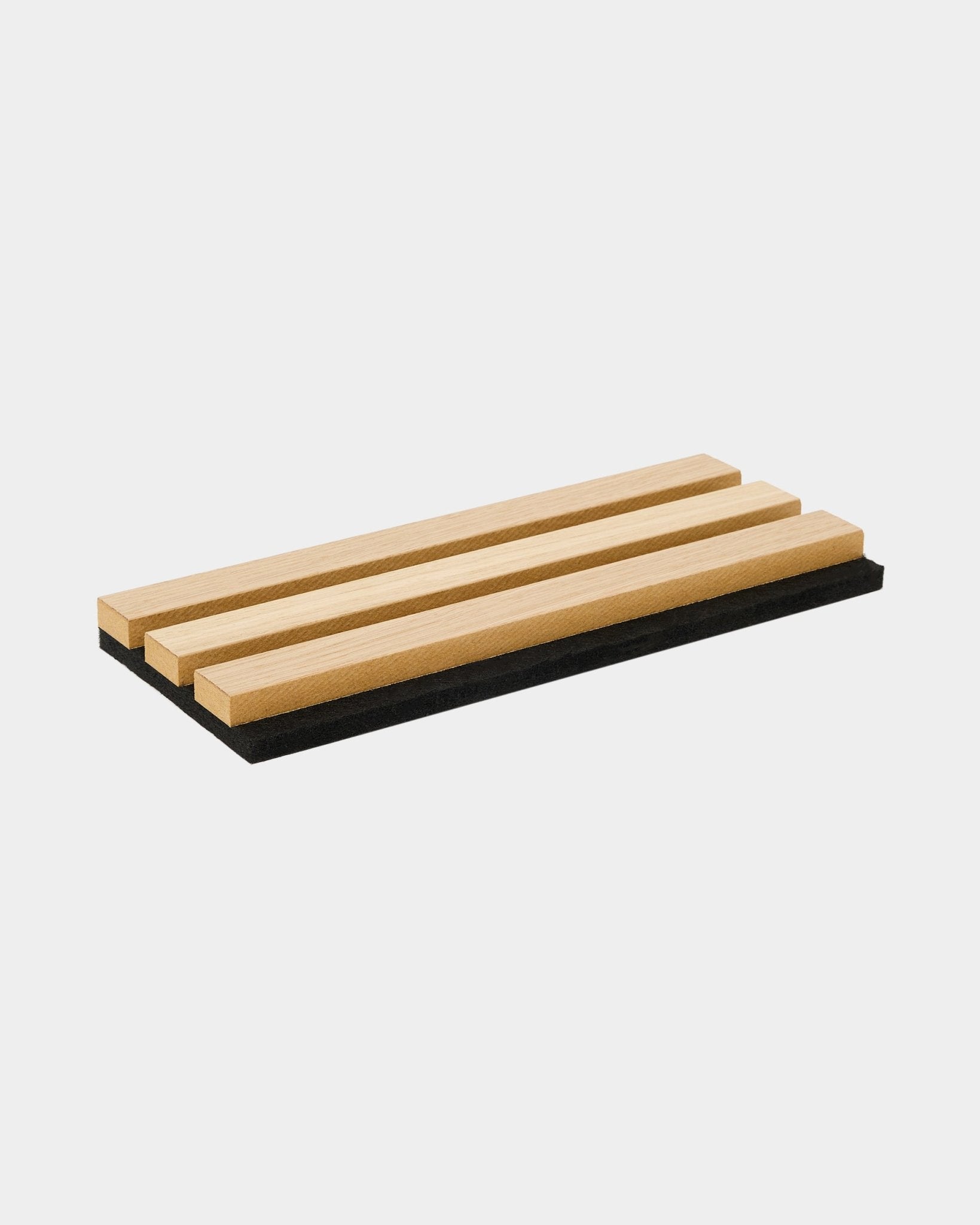 Il vassoio campioni WoodUpp Akupanel in Classic Rovere presenta tre doghe in legno acustiche su una base in feltro black, mettendo in risalto il design nordico e il contrasto tra i materiali.