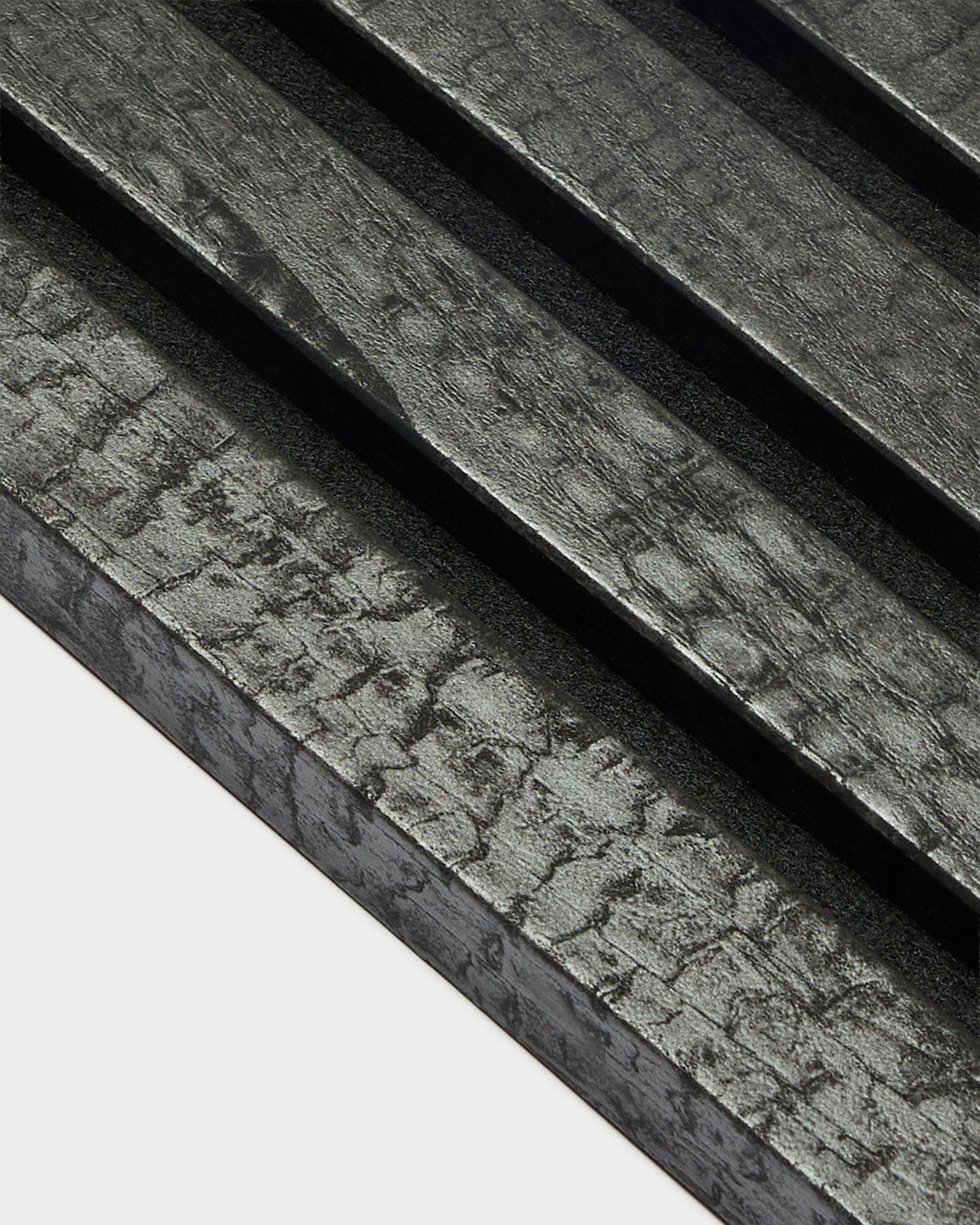 Lamella terminale WoodUpp Akupanel in Charcoal (2,2 cm), con pannelli acustici in legno diagonali e testurizzati con finitura black bruciata, per installazione a parete.