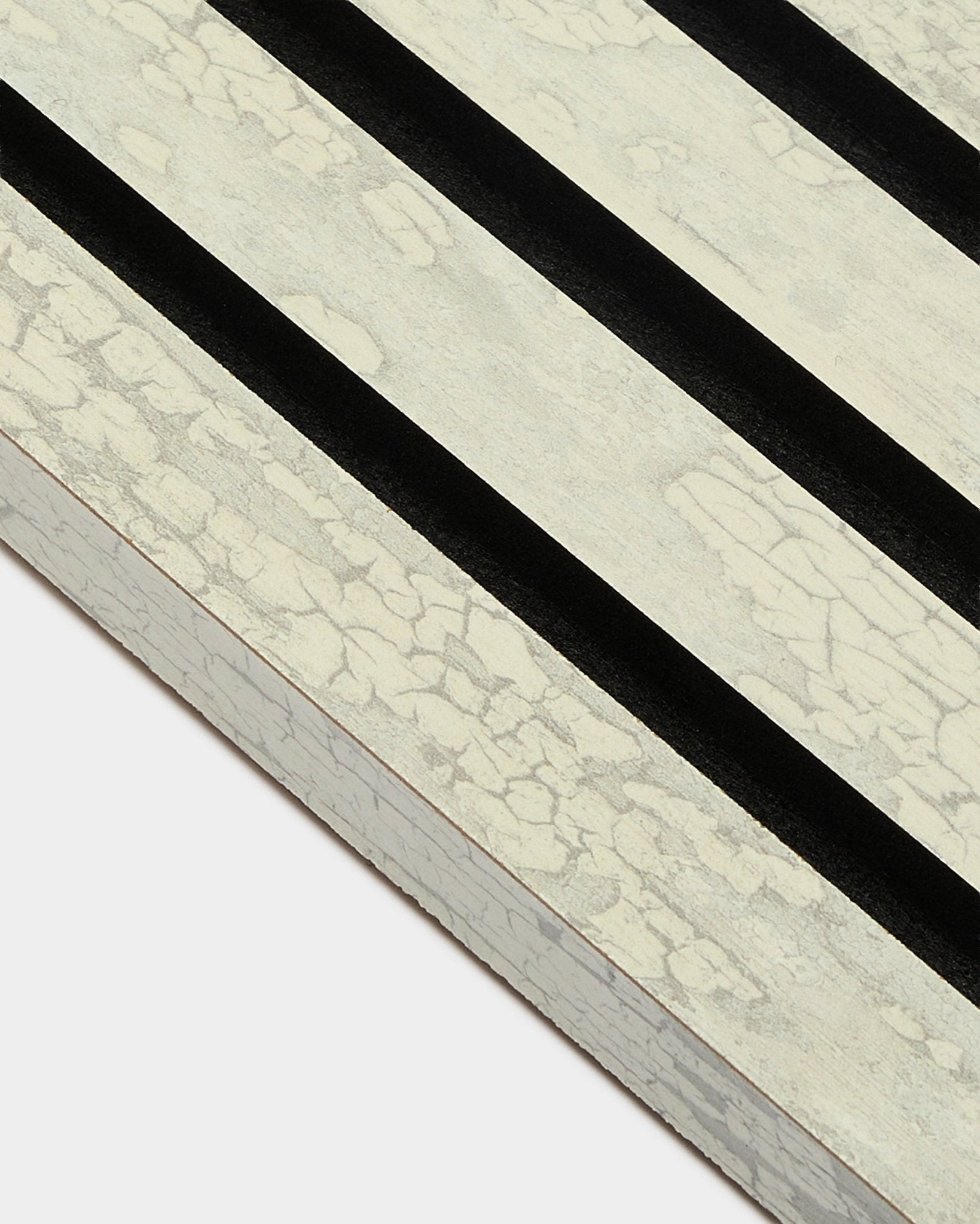 Primo piano della lamella terminale WoodUpp Akupanel in Oxide White (2,2 cm) con tre strisce diagonali black su un telaio MDF Pannello acustico.