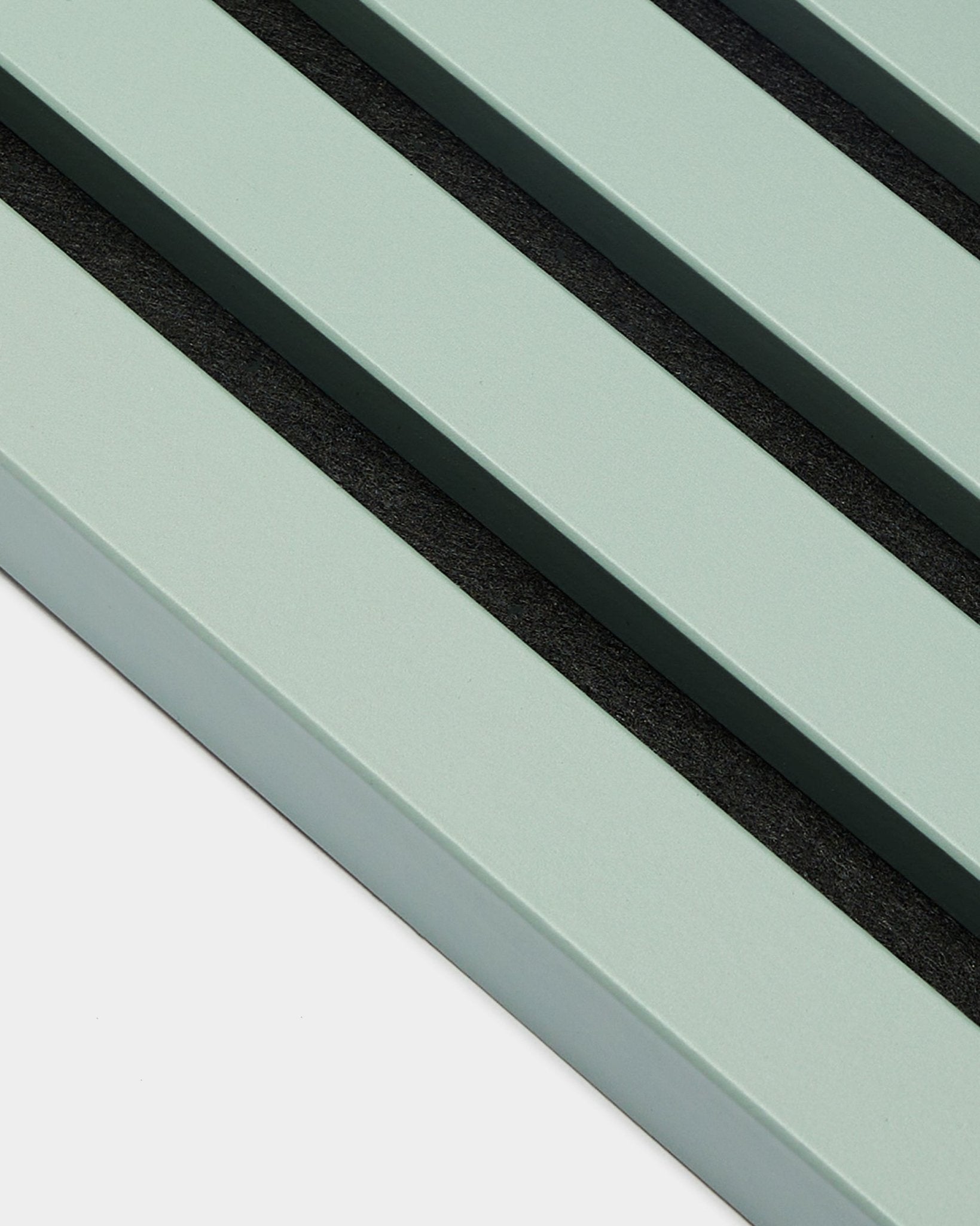 Primo piano di tre doghe End Lamella / Cloud verde pastello parallele, larghe 2,2 cm, di WoodUpp, come parte di un Akupanel Pannello acustico su uno sfondo chiaro.