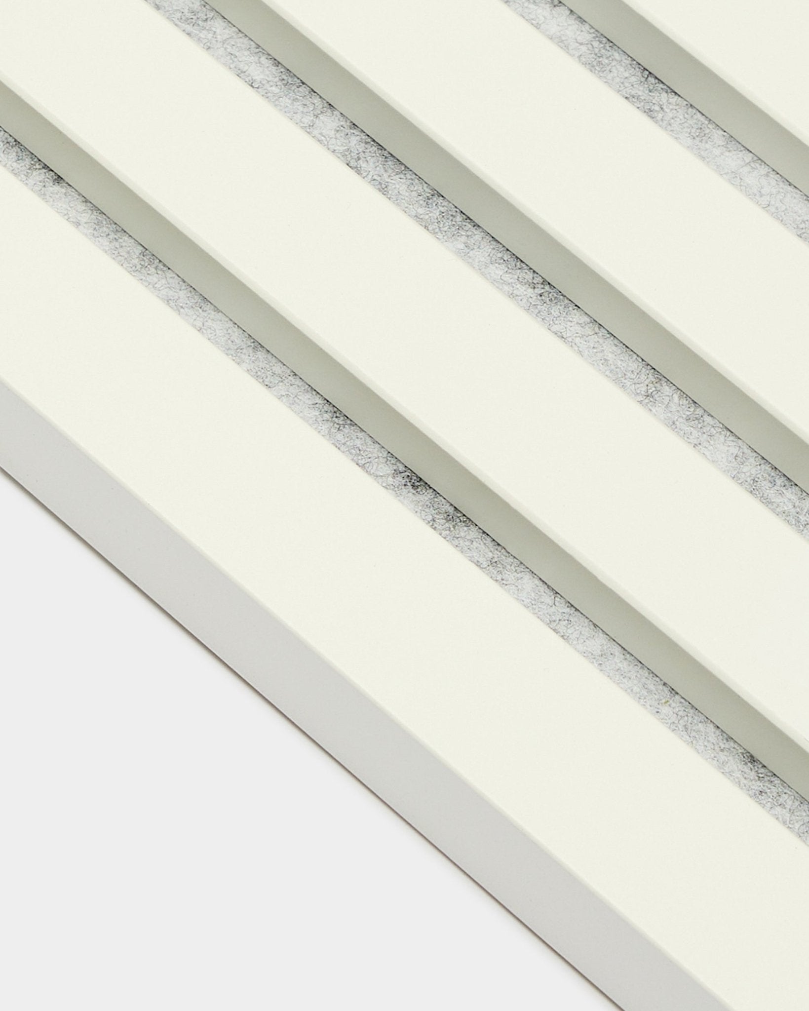 Quattro pannelli acustici WoodUpp Akupanel End Lamella/Snow (2,2 cm) disposti in diagonale, con doghe bianco sporco e interspazi grigi testurizzati in stile nordico.