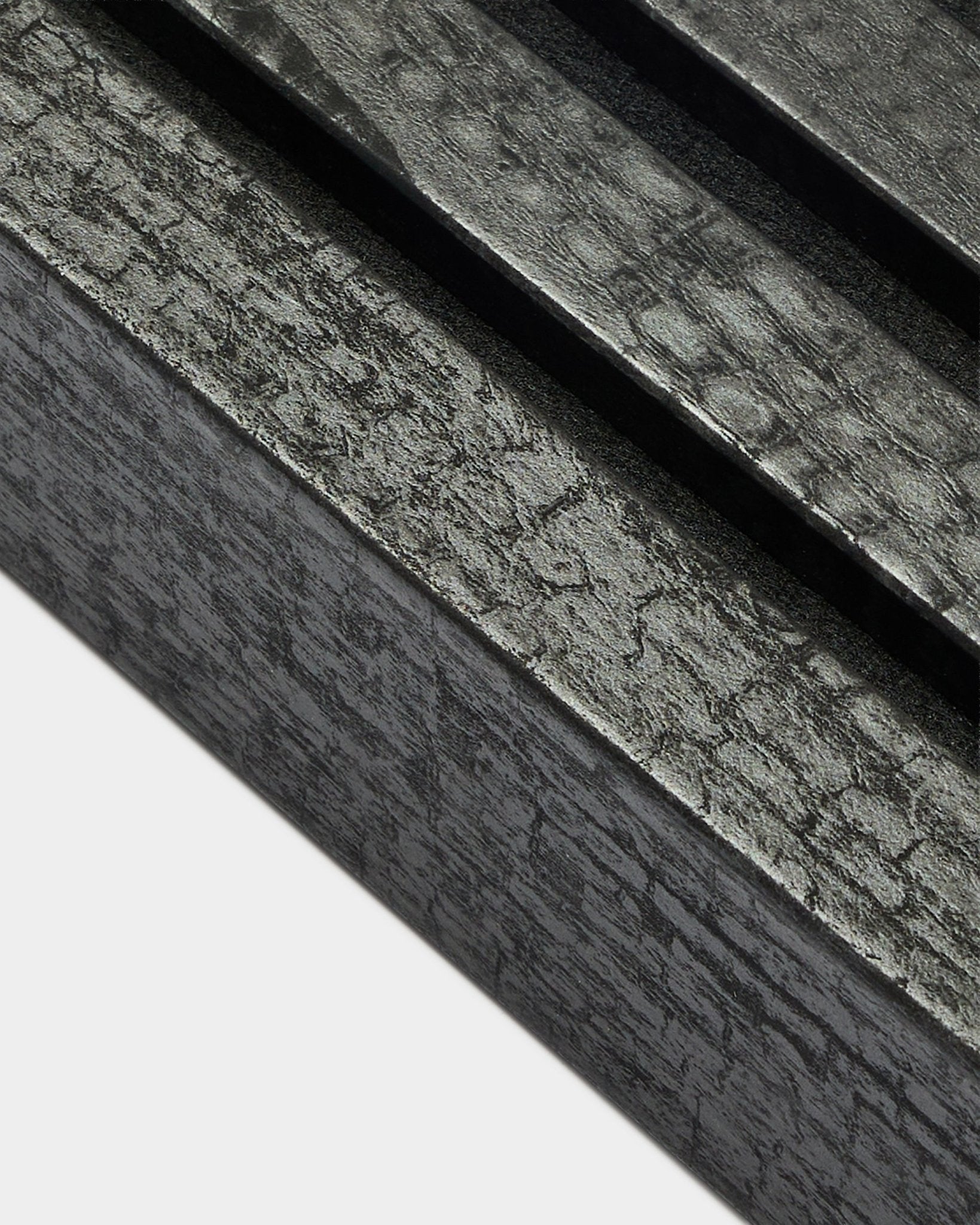 Primo piano della lamella terminale WoodUpp Akupanel in Charcoal, larga 6,7 cm, con doghe acustiche parallele e una caratteristica texture della venatura del legno.