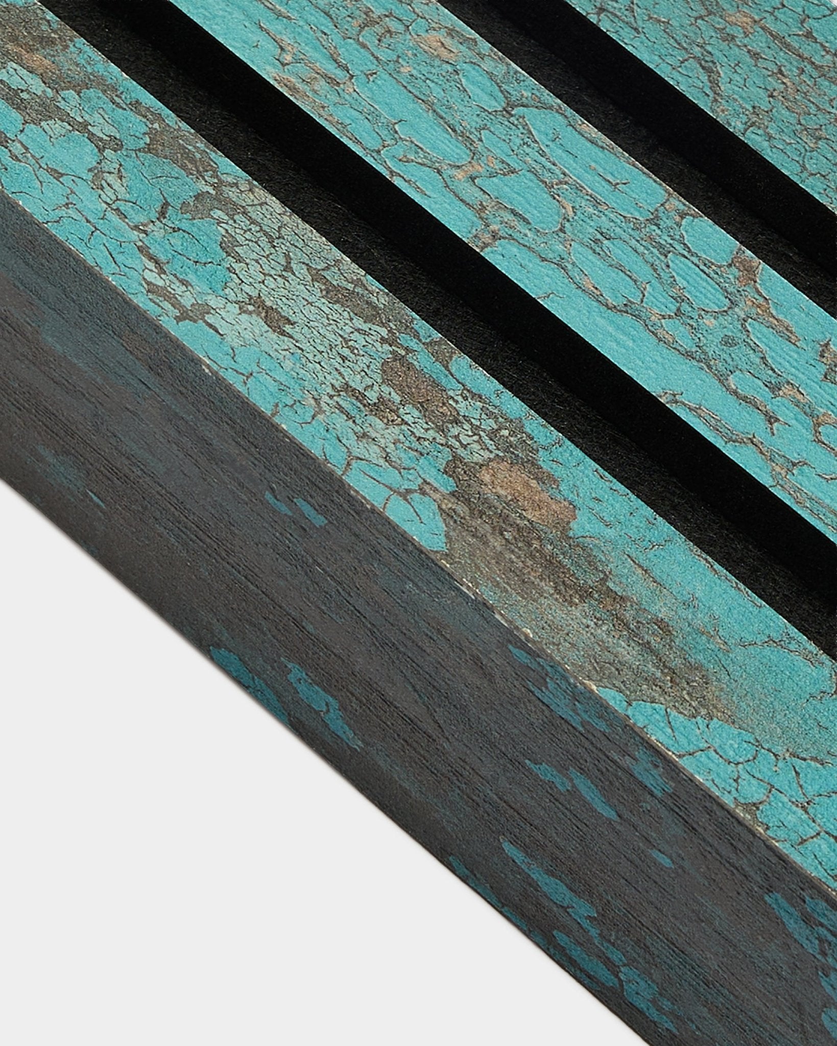 Primo piano della lamella terminale WoodUpp Akupanel in Oxide Blue, larga 6,7 cm, con vernice blu screpolata e scanalature black su una superficie Pannello acustico rustica.