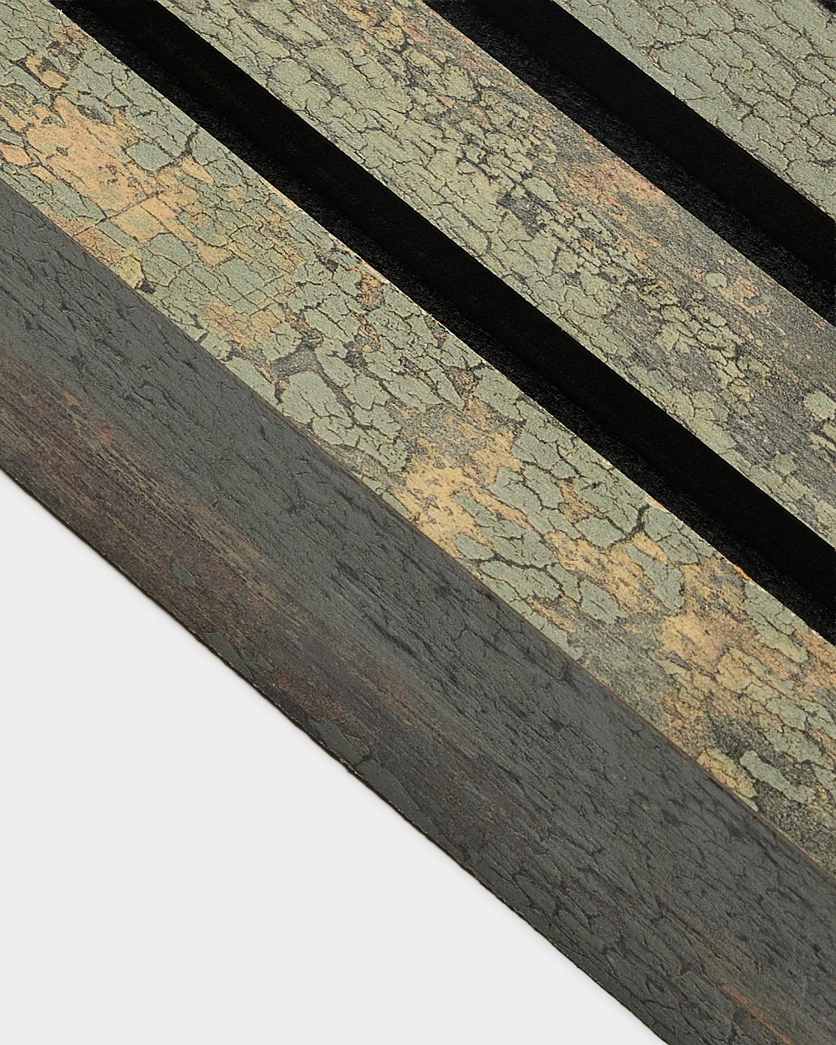 Primo piano della lamella terminale WoodUpp Akupanel in Oxide Grey, larga 6,7 cm, con una finitura Pannello acustico materica, due scanalature black e una struttura in MDF.