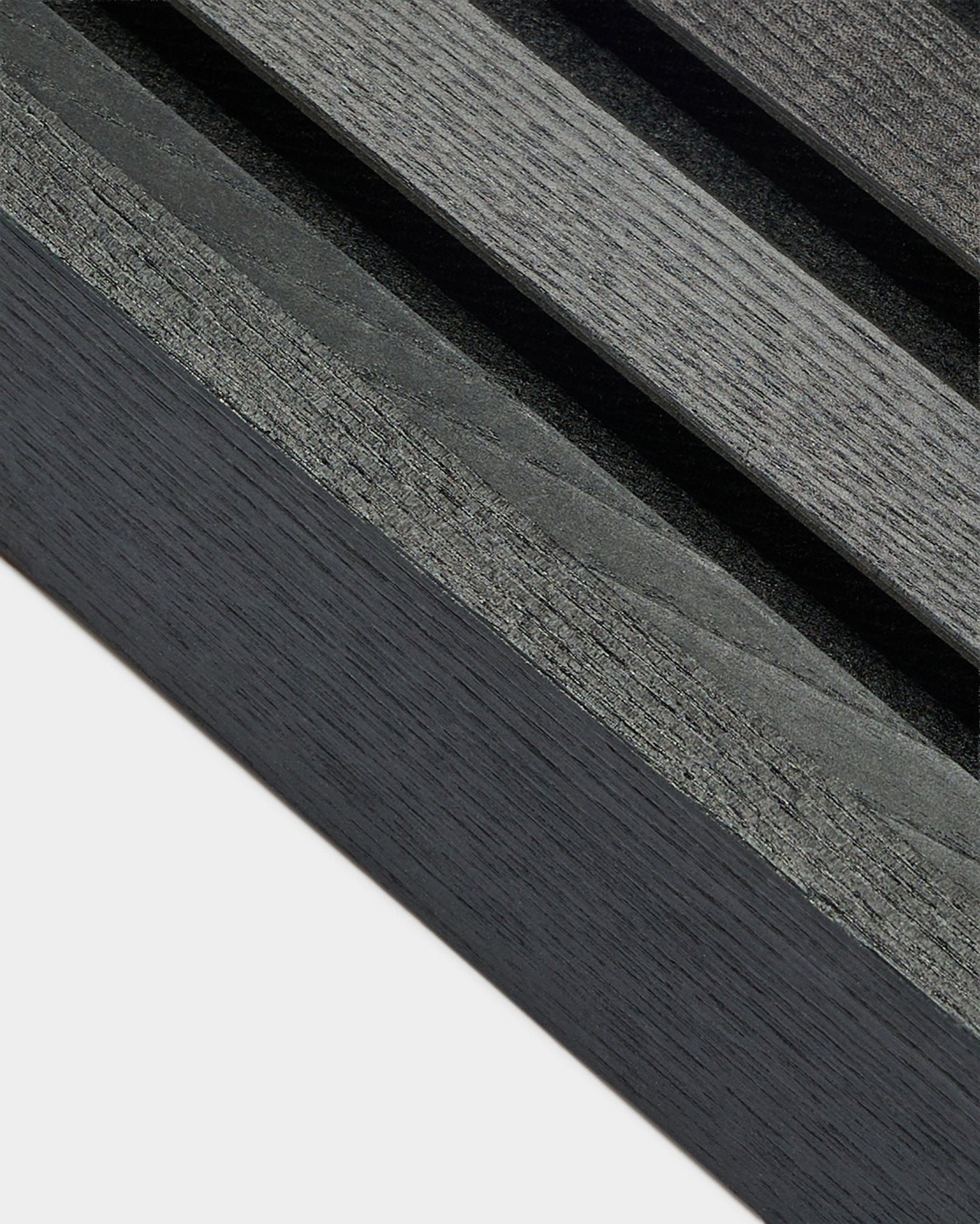 Primo piano della lamella terminale WoodUpp Akupanel in frassino Black (6,7 cm), che mostra venature del legno grigio scuro su una base chiara, progettata per installazioni nordiche Pannello acustico.