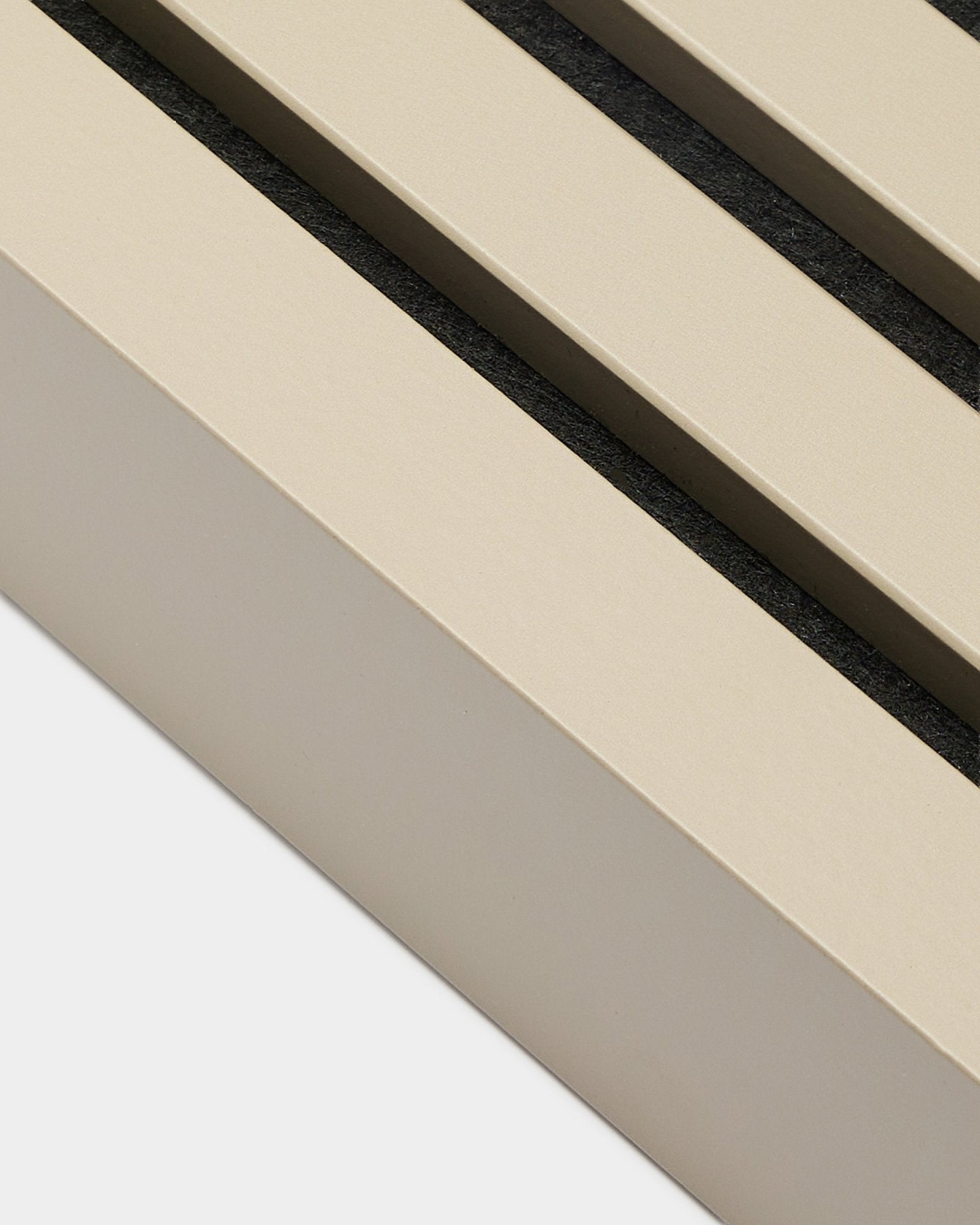 Primo piano di WoodUpp End Lamella nella finitura Stone, largo 6,7 cm: accessorio di installazione per telai in MDF o pannelli acustici Akupanel. Doghe del pannello Beige con spazi black.
