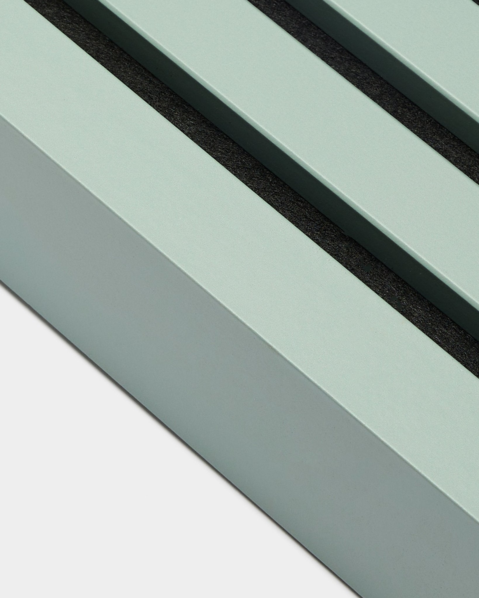 Primo piano dell’accessorio di installazione WoodUpp Akupanel: lamella terminale in Cloud, larga 6,7 cm, cornice in MDF verde menta con due scanalature black su sfondo bianco.