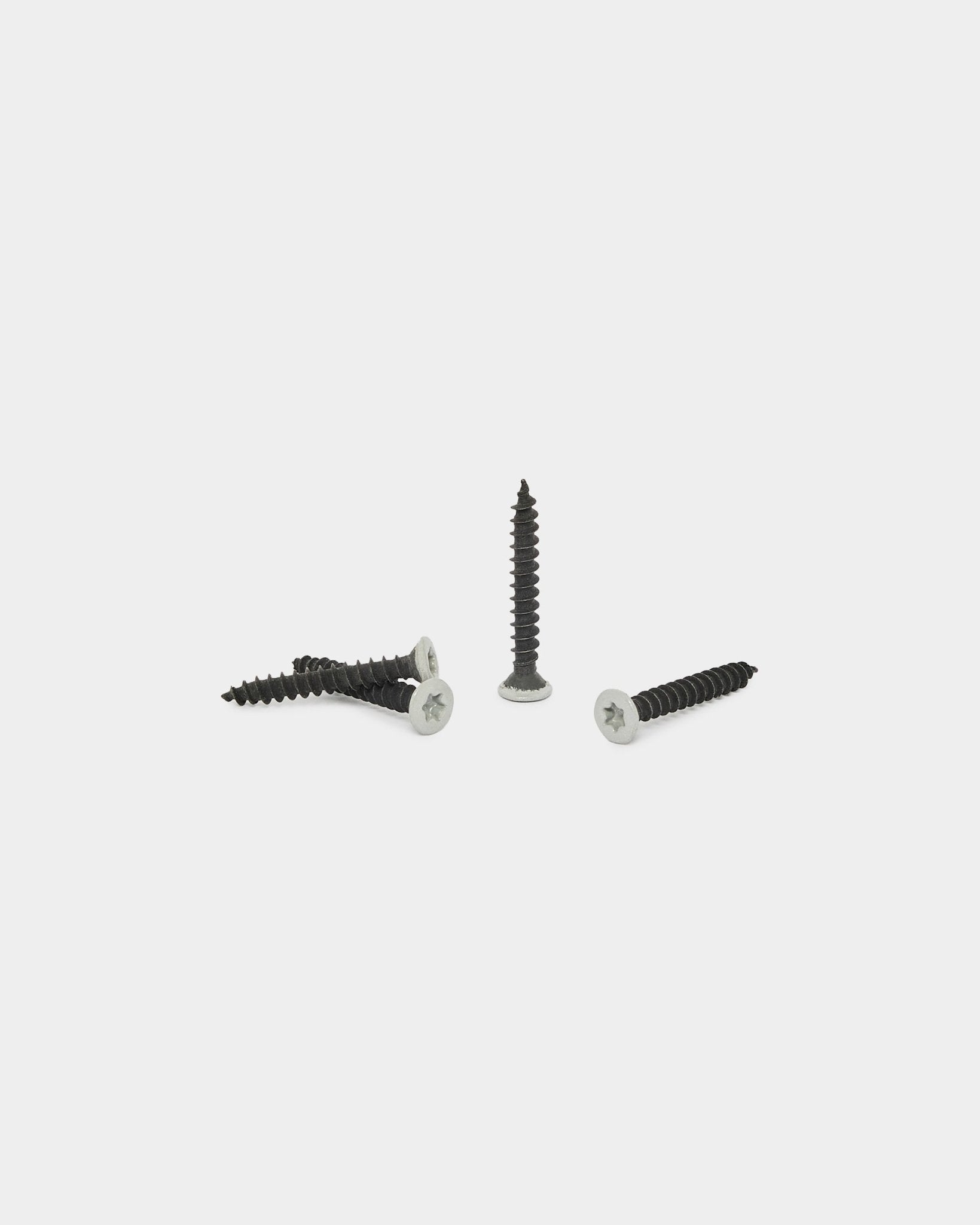 Quattro viti WoodUpp grey del set Prodotti per l’installazione (100 pz) su uno sfondo bianco semplice; tre sono horizontal e una è in posizione verticale.