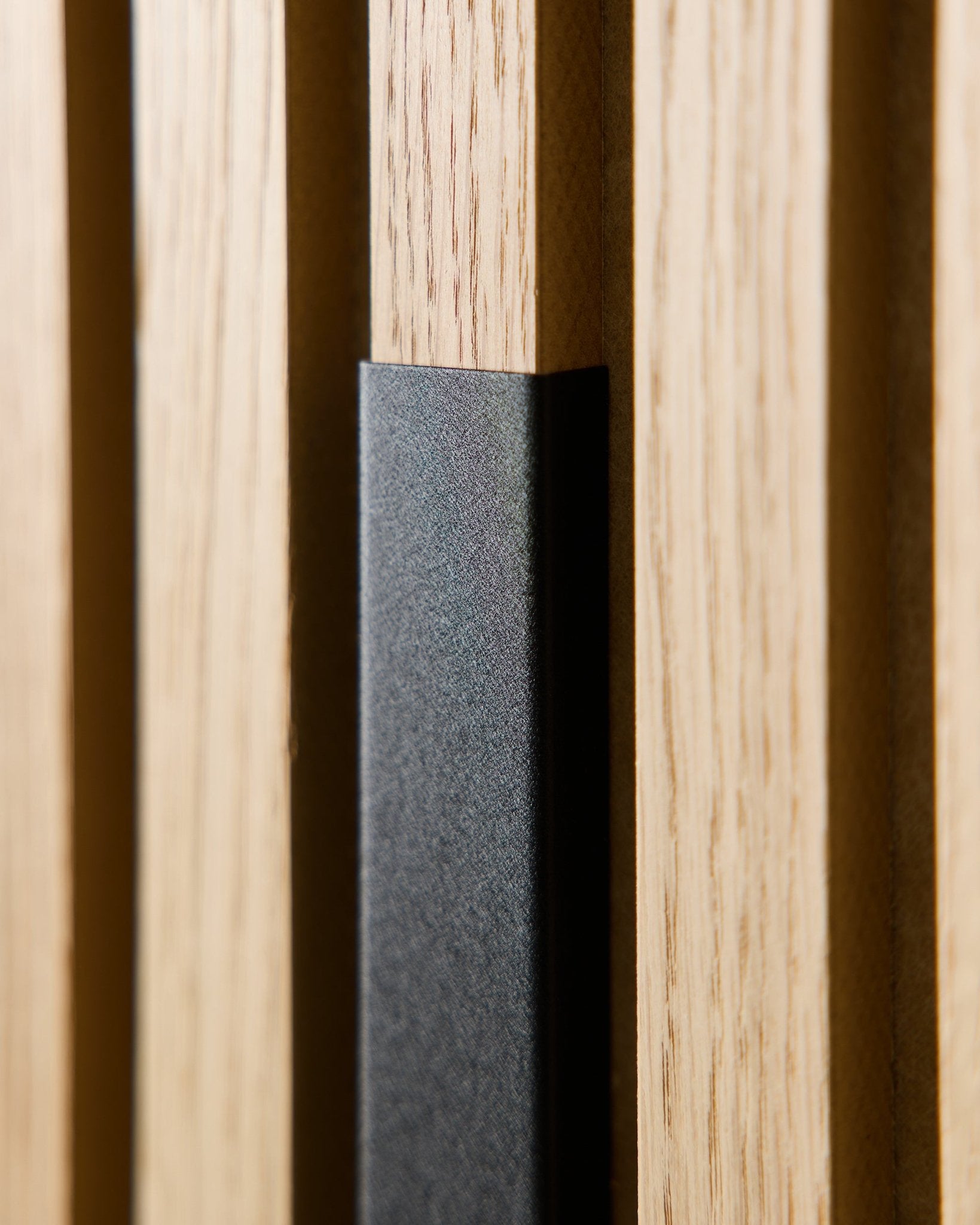 Primo piano di WoodUpp Liva Pannello acustico con rivestimento in alluminio black da 60 cm, che mostra doghe in legno vertical e un accento black per interni moderni in stile nordico.