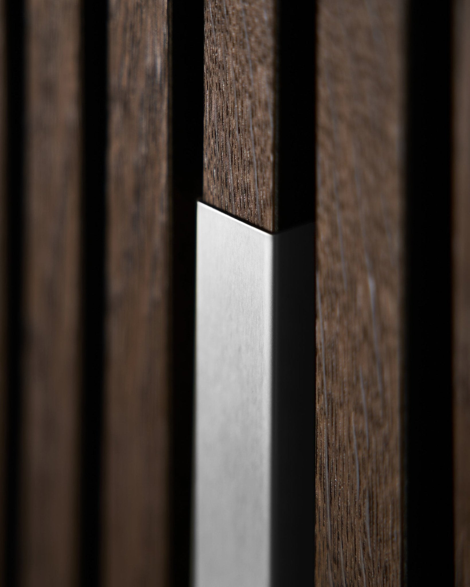 Primo piano di WoodUpp Akupanel Liva | Cover–20 cm in steel lucido con doghe in legno vertical, che mette in evidenza la texture nordica e il contrasto di questo Pannello acustico.