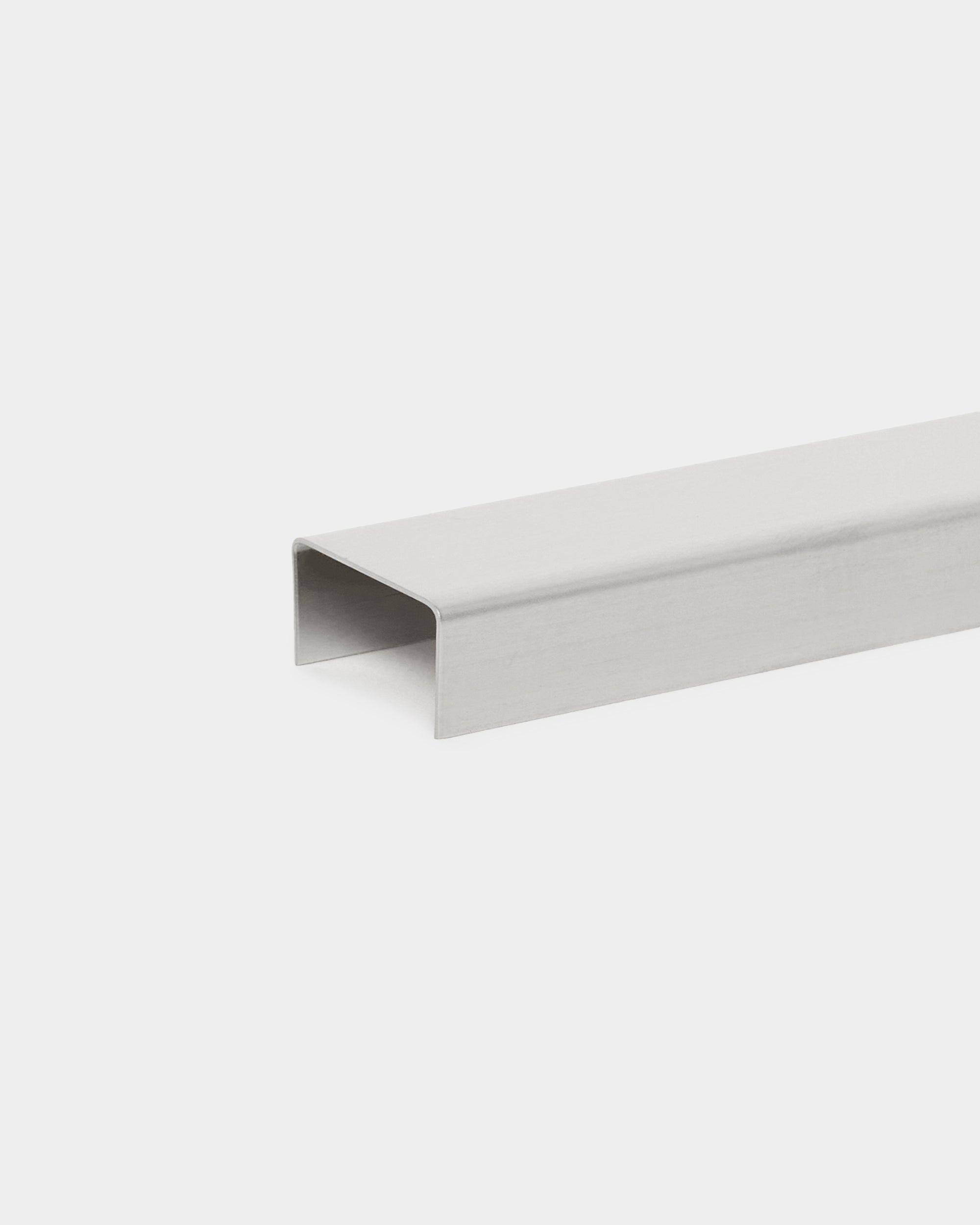 La Liva Cover di WoodUpp, un accessorio con profilo a U in steel lucido da 20 cm, pensato come rivestimento da parete minimalista per pannelli acustici Akupanel su sfondi bianchi.