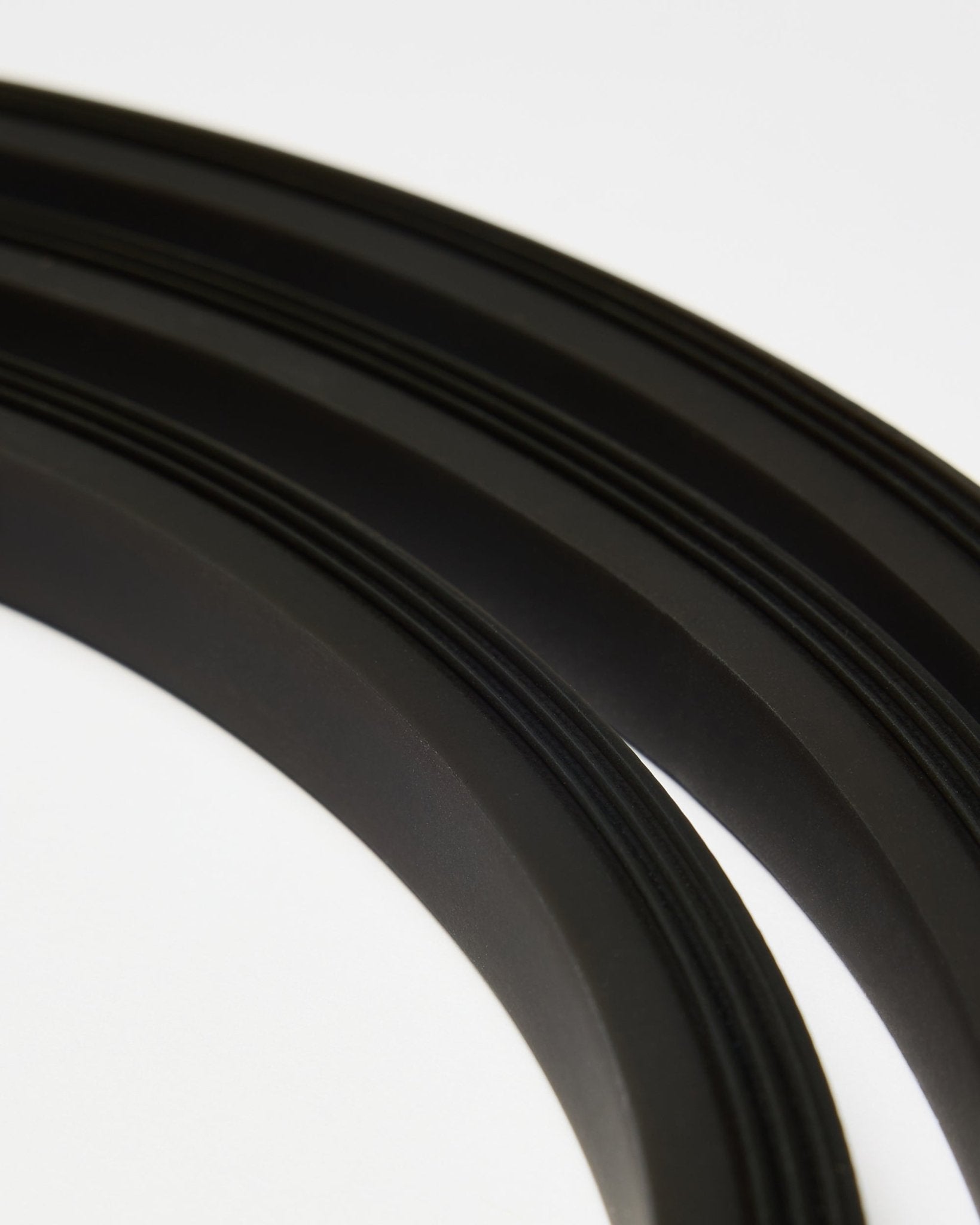 Primo piano della striscia LED Lumi black di WoodUpp (300 cm), disposta in linee curve su sfondo bianco, in armonia con lo stile minimalista Akupanel Pannello acustico.