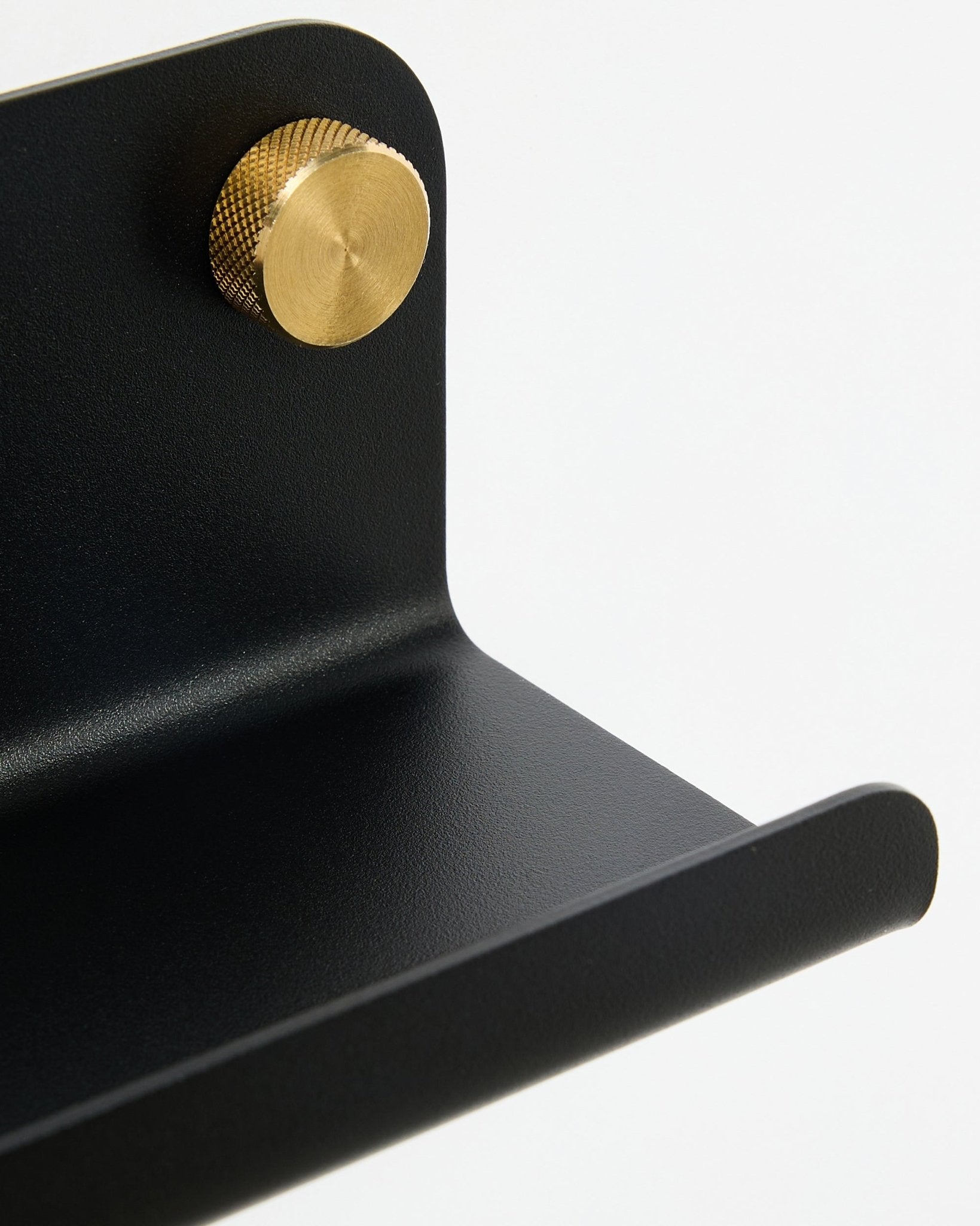 Primo piano della mensola stretta WoodUpp Norr, 35,9 cm, black steel con bordo curvo e pomello dorato, mostrata su sfondo bianco.