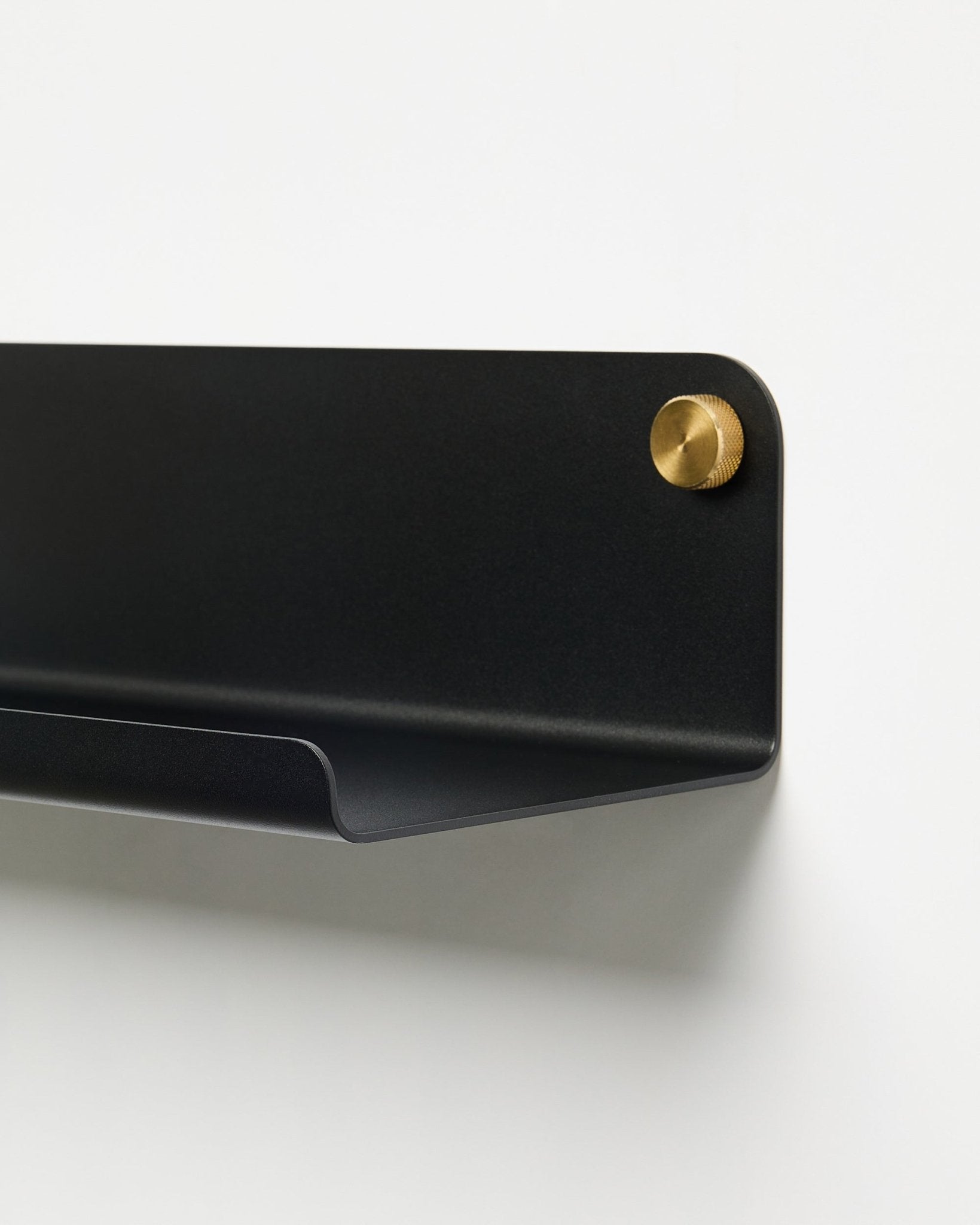 Primo piano dell’accessorio mensola larga WoodUpp Norr (51,9 cm) in metallo black verniciato a polvere con vite dorata, su uno sfondo bianco semplice.