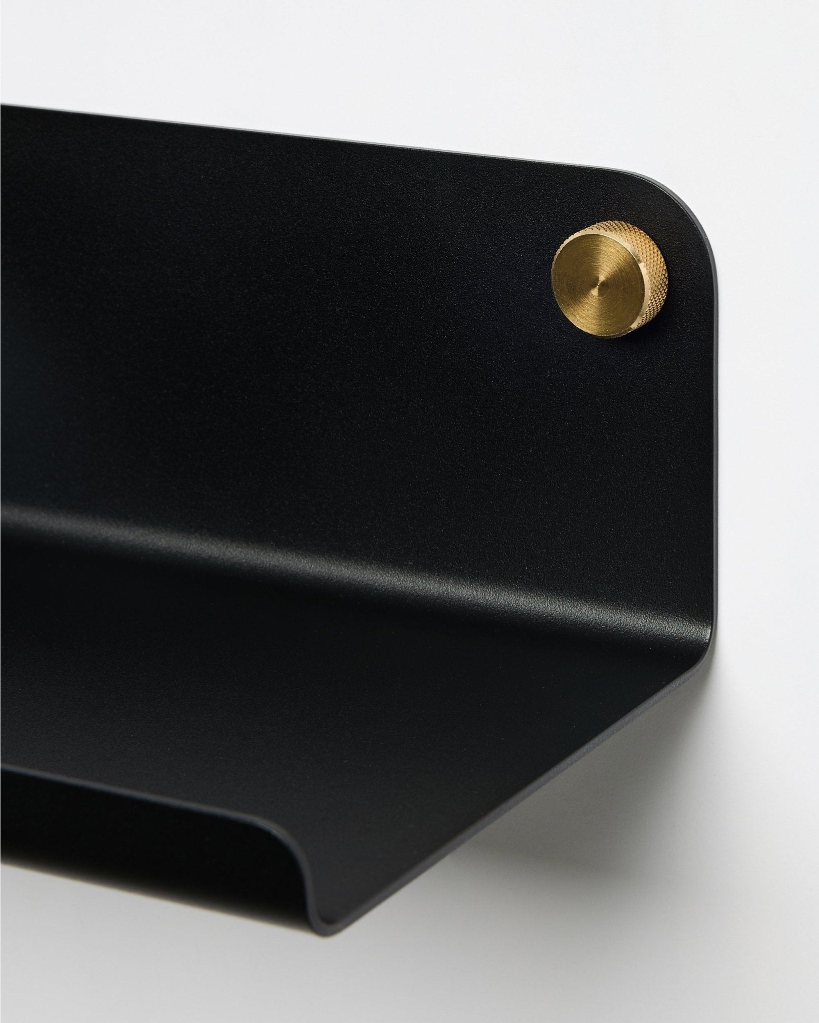 Primo piano della mensola larga WoodUpp Norr in black, 35,9 cm, con bordo curvo, fissata alla parete con una vite rotonda brass. Design nordico minimalista.