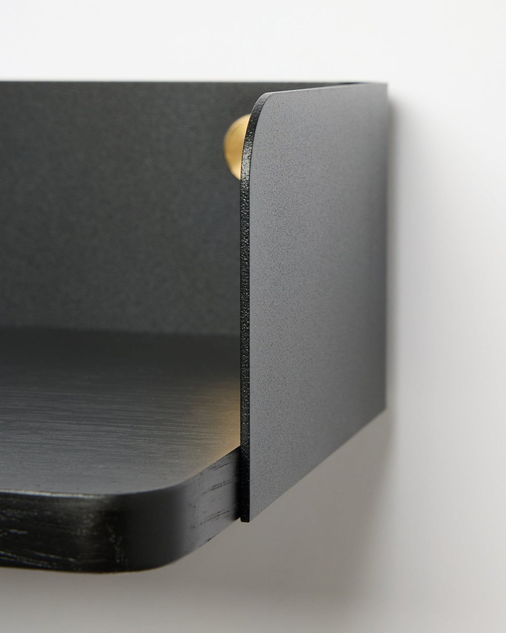 Dettaglio della libreria Linn di WoodUpp in Black Oak, larga 39,9 cm, con bordi arrotondati e finitura opaca, montata su una parete bianca. Stile minimalista nordico.