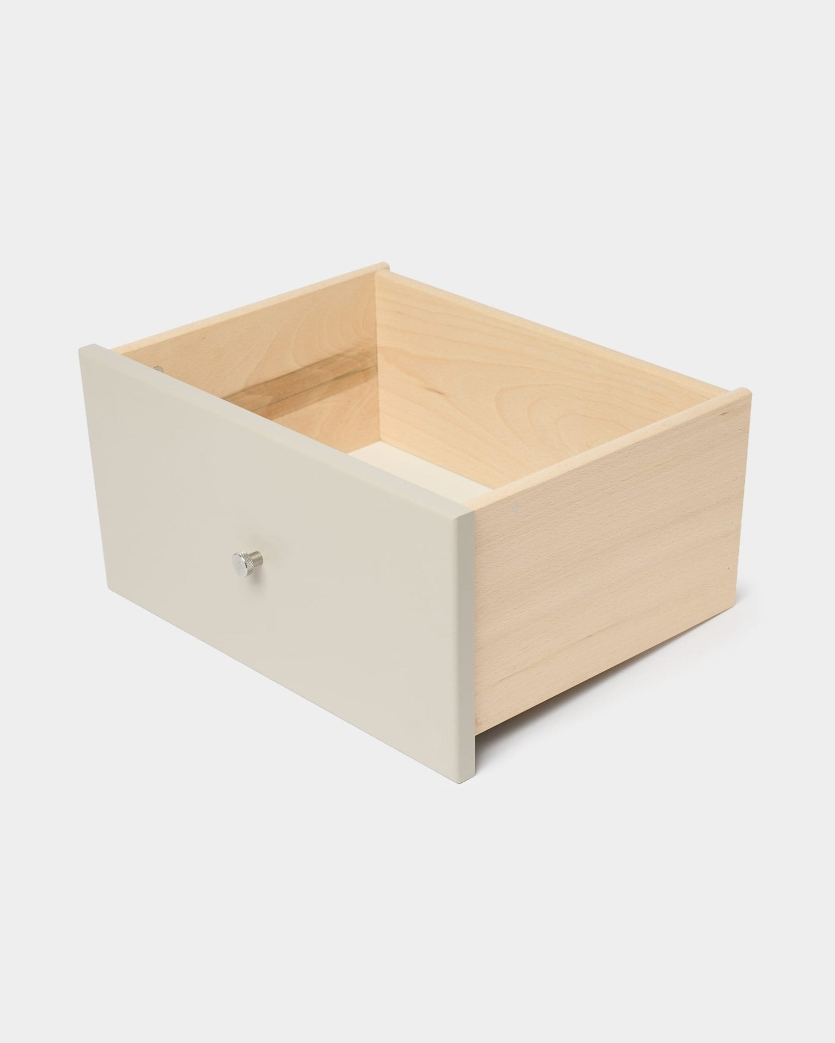 Cassetto per libreria WoodUpp Arka in beige con pannello frontale e pomello bianchi, progettato per riporre oggetti al chiuso, raffigurato su uno sfondo bianco a tinta unita.