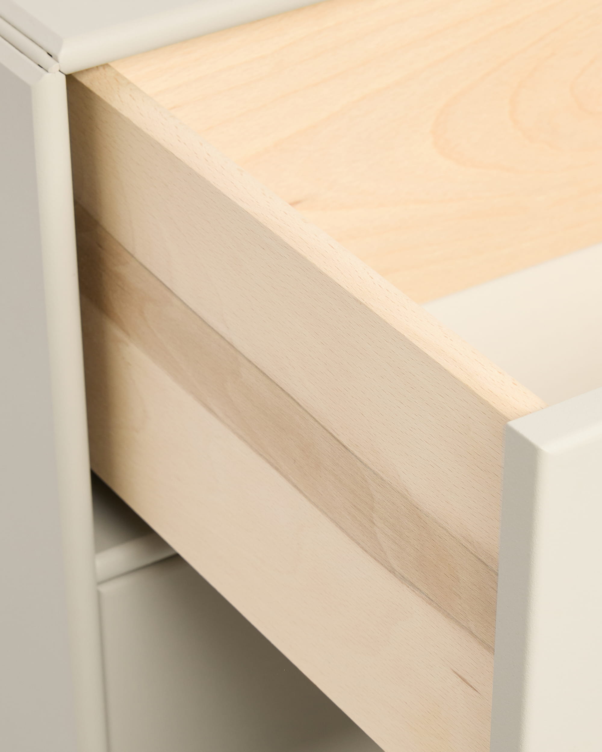 Primo piano di un cassetto beige della libreria Arka di WoodUpp, parzialmente aperto, all’interno di un mobile bianco, con maniglie della collezione CREATE.