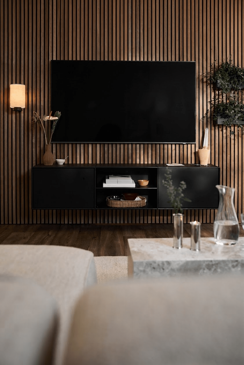 Soggiorno moderno con mobile TV WoodUpp Arka nero, parete a doghe Akupanel, dettagli minimalisti e un divano chiaro con tavolino.