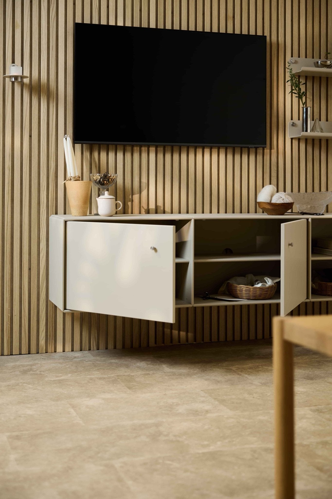 Soggiorno moderno con il mobile TV Arka in beige di WoodUpp, posizionato sotto un mobile e un televisore, su una parete acustica nordica in doghe di legno Akupanel. Arredamento modulare.