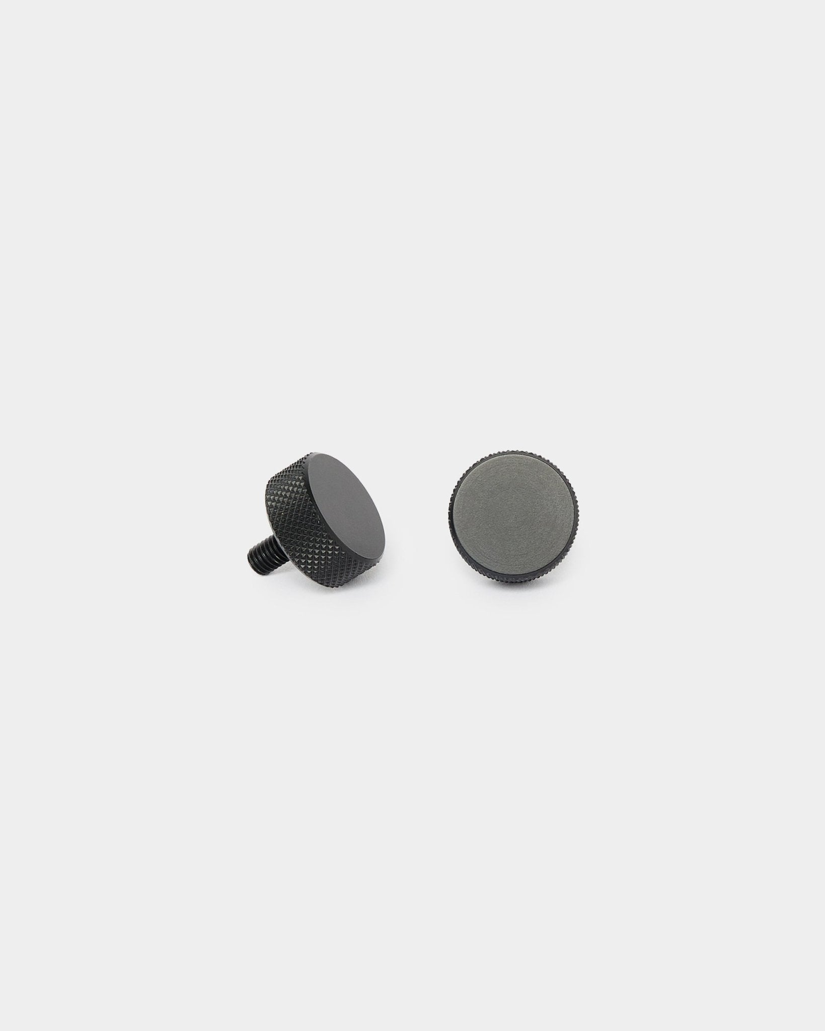 Due viti Finger WoodUpp black (2 pz, M5x10mm, 20x8.8) mostrate in posizione verticale e adagiate su un lato, su uno sfondo bianco semplice, per l’installazione di Akupanel.