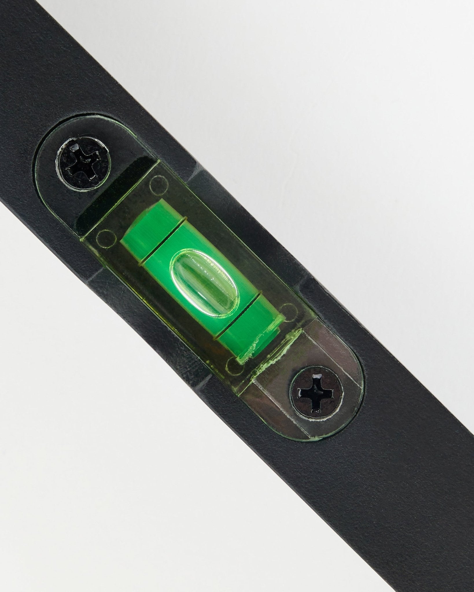 Primo piano di una livella a bolla WoodUpp black (15 x 3,2 cm) con fiala verde, usata per l’installazione precisa dei pannelli acustici.