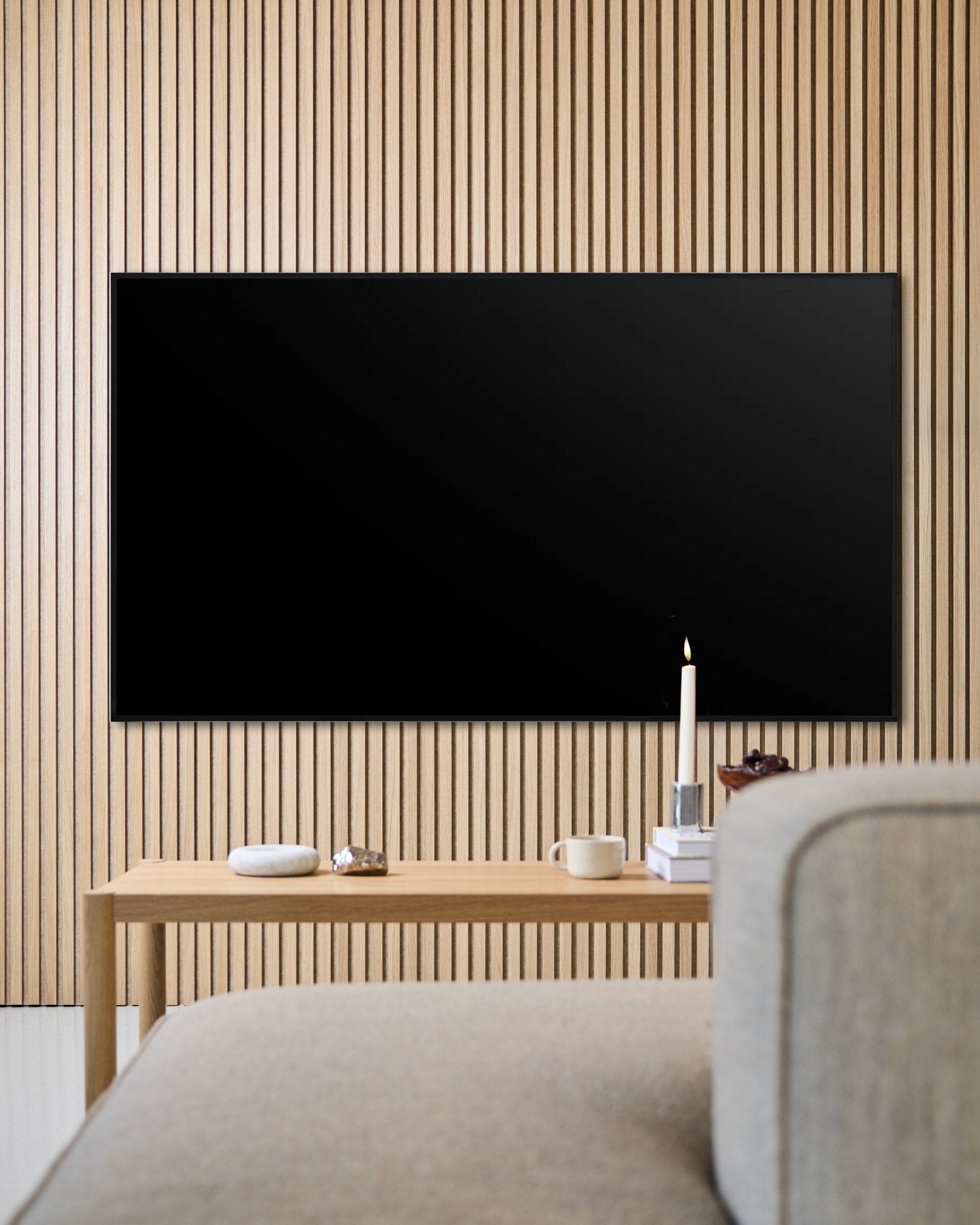 Soggiorno moderno con TV a schermo piatto montata a parete, parete con doghe acustiche in legno Akupanel e tavolino in legno per un’atmosfera accogliente.