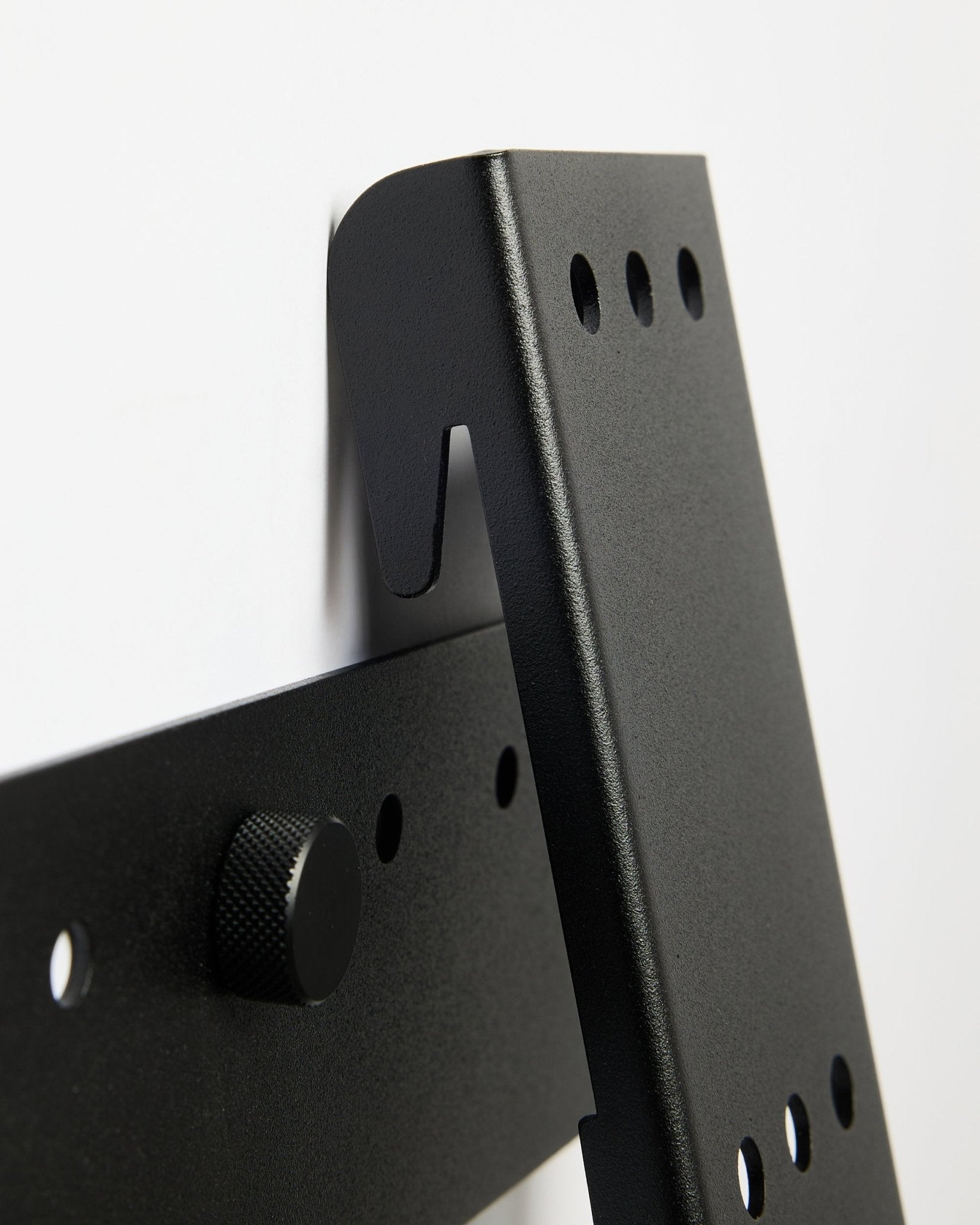 Supporto TV WoodUpp Fjell (large), una staffa in metallo black per TV da 85 pollici con VESA 600x400, montata su una parete bianca.