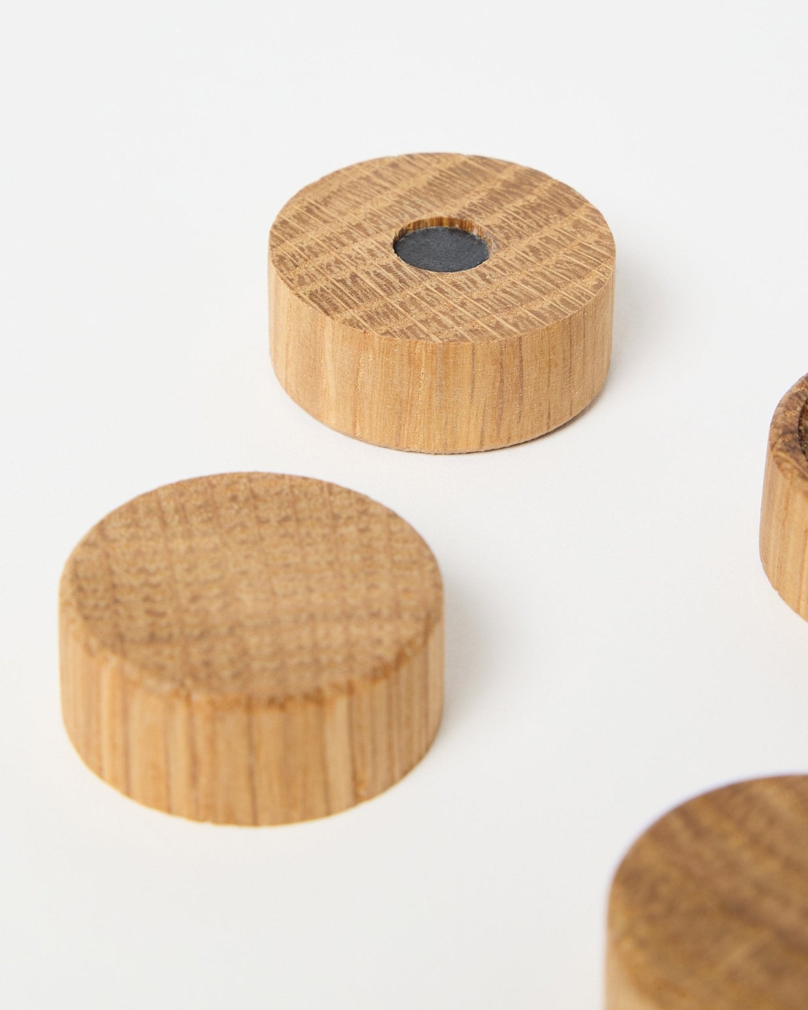 Set di quattro magneti natural oak di WoodUpp, progettati per l’uso con i pannelli acustici in legno Akupanel, uno dei quali con un magnete centrale in neodimio per una presa extra, mostrati su sfondo bianco.