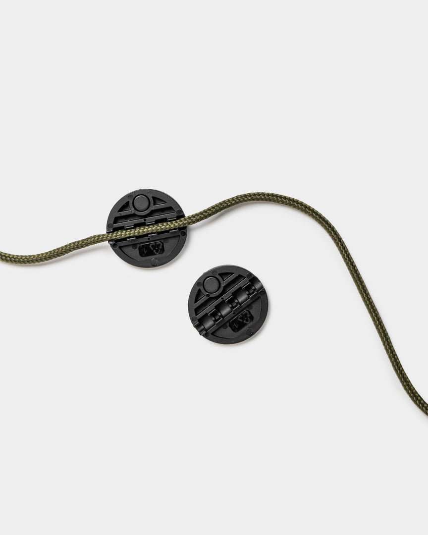 Due Vindar Progetti String cord locks di WoodUpp con cordino intrecciato verde, mostrati su uno sfondo semplice grigio chiaro.