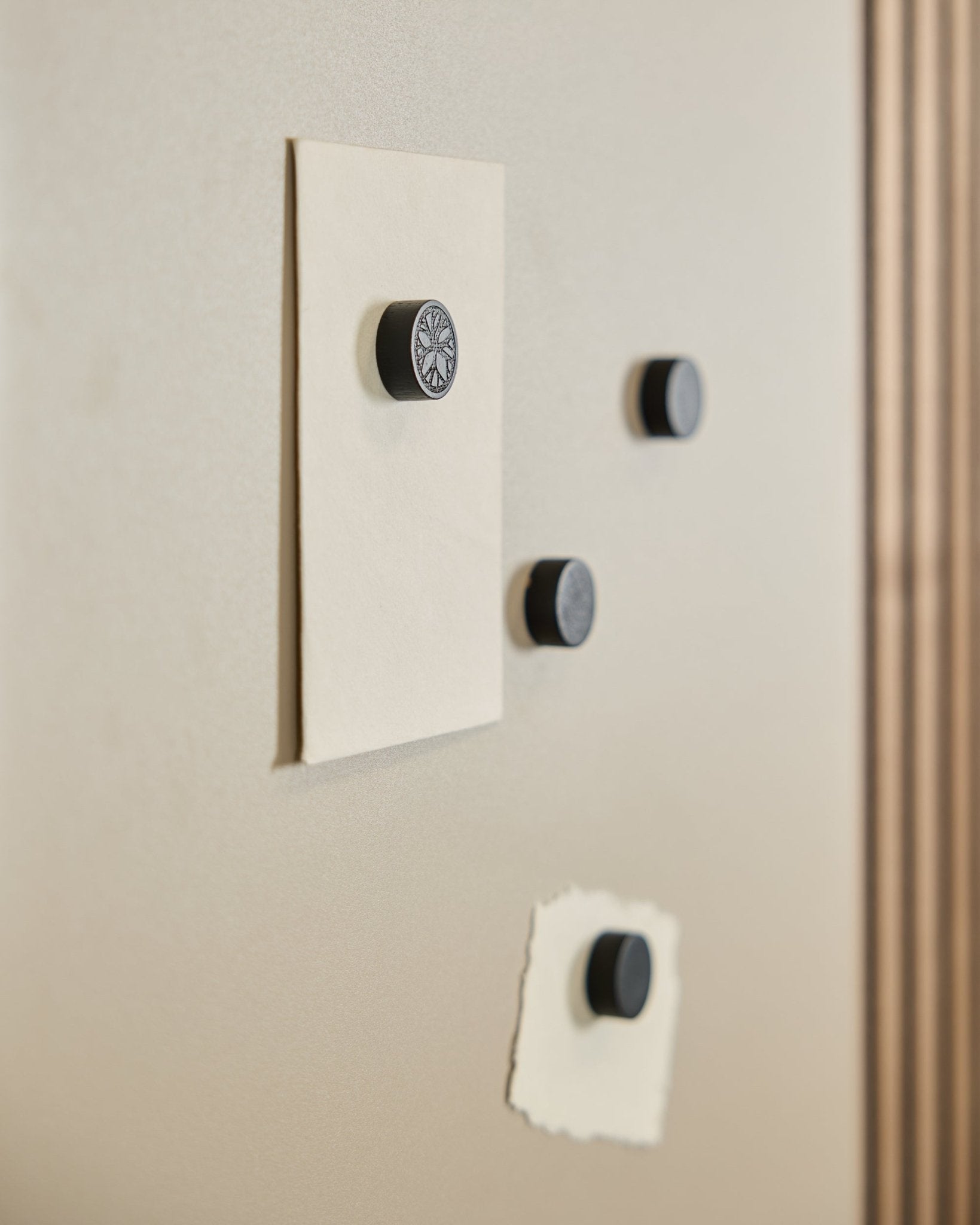 Quattro magneti WoodUpp Norr in Black Oak (4 pz) fissano due fogli a una lavagna magnetica Norr, con una parte di Pannello acustico visibile sulla destra.