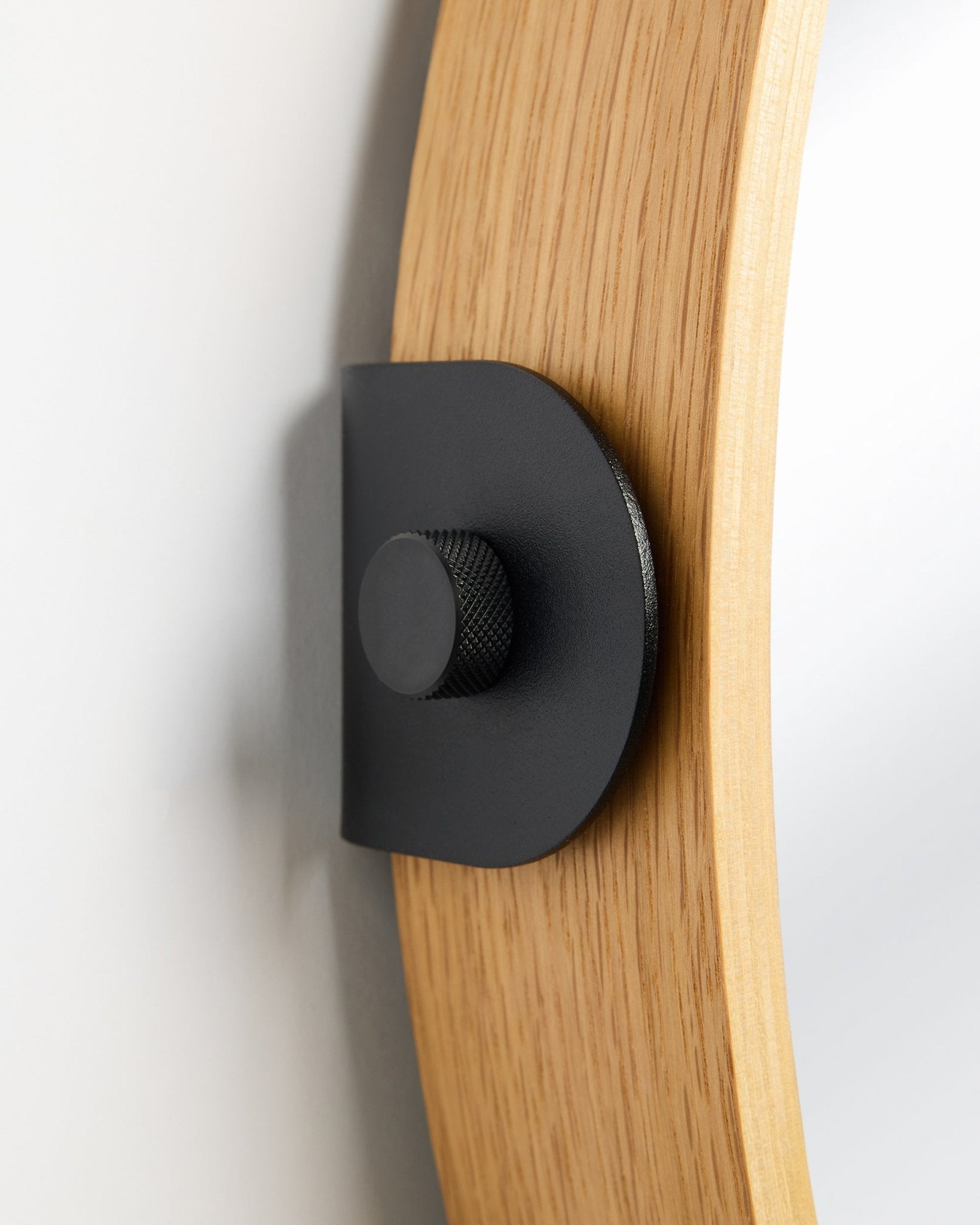 Dettaglio dello specchio Linn di WoodUpp in Natural Oak, un accessorio Pannello acustico fissato alla parete con una staffa in metallo black e un pomello rotondo.