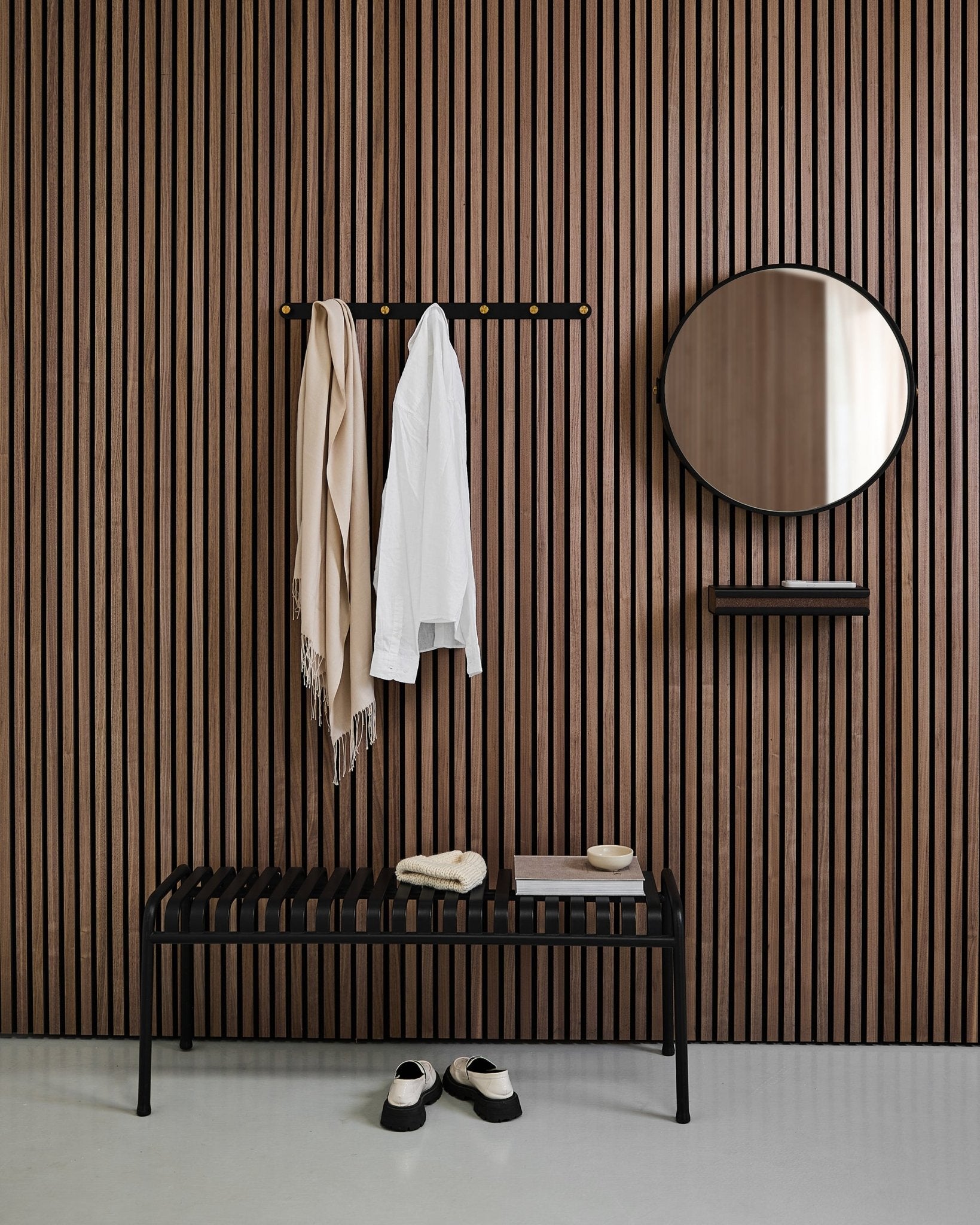 Ingresso minimalista con un WoodUpp Linn | Mirror in Black Oak, pannello acustico nordico a doghe, panca, mensola, cappotto e sciarpa appesi, e scarpe sul pavimento.
