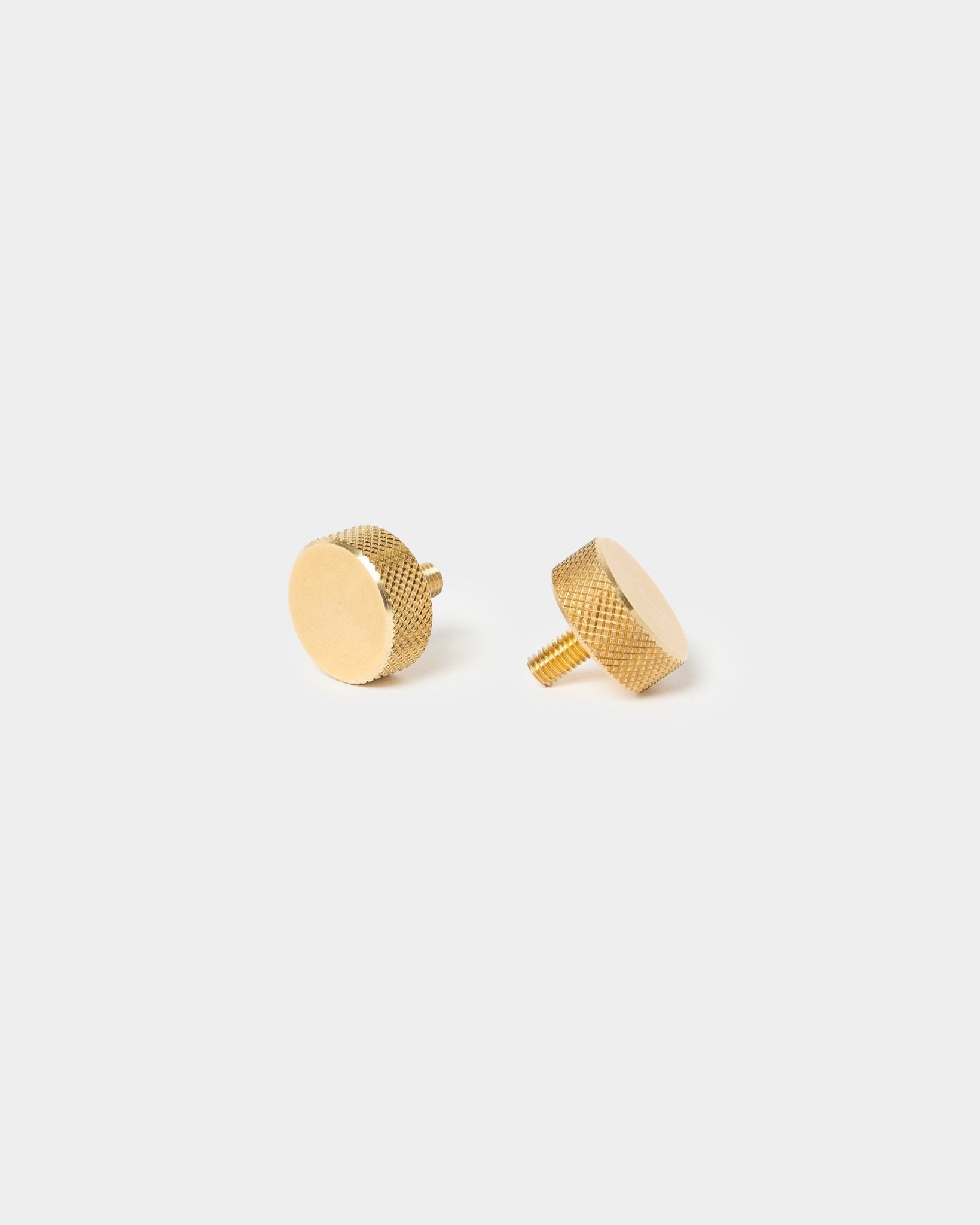 Coppia di viti zigrinate WoodUpp brass (M5x10 mm, 20x8.8), con bordi testurizzati e steli corti, pensate per gli accessori Akupanel, su uno sfondo chiaro uniforme.