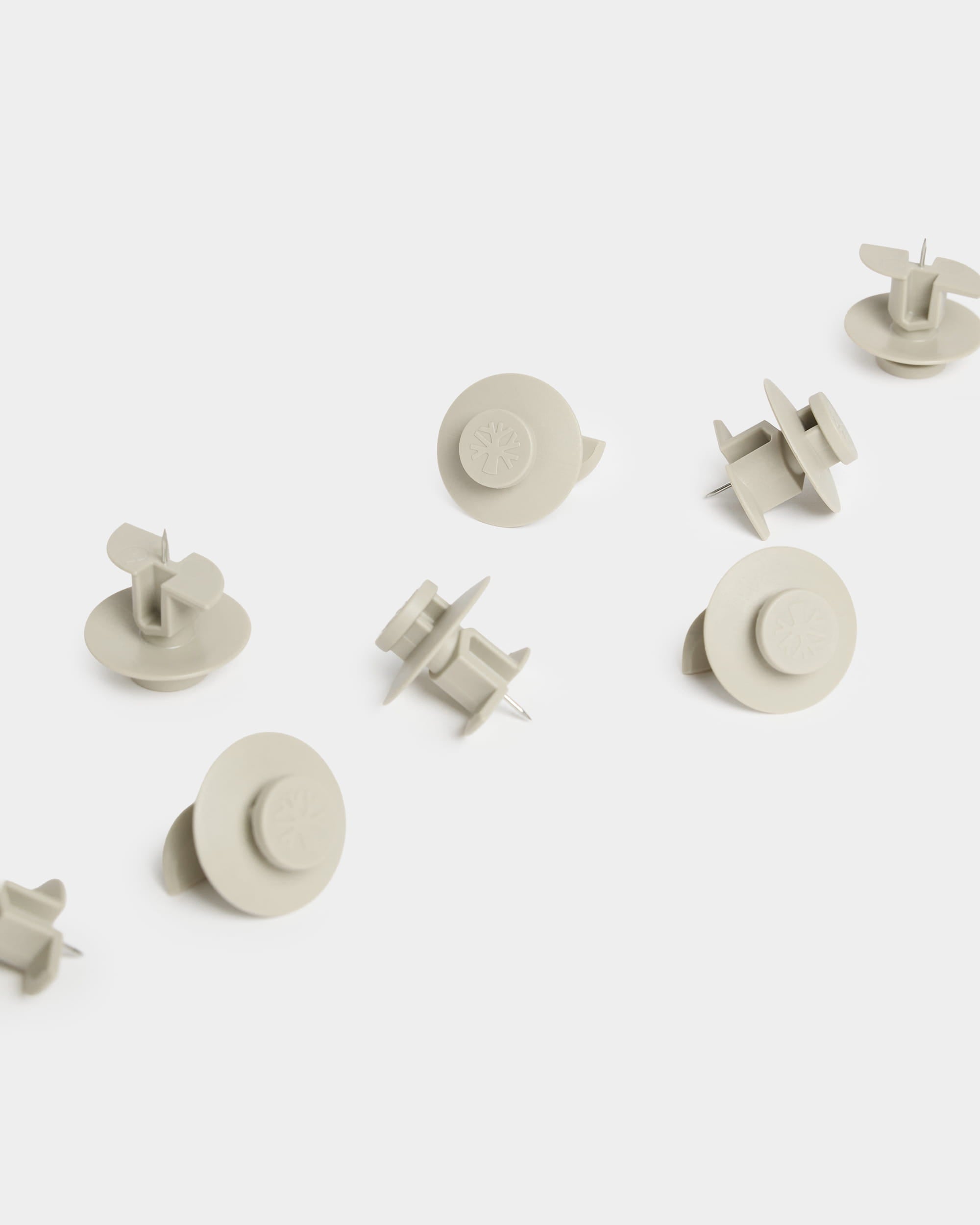 Dieci puntine da disegno WoodUpp Dupps color beige (Light) con testina circolare sono disposte su una superficie bianca; sono progettate per luso con accessori per pannelli acustici.