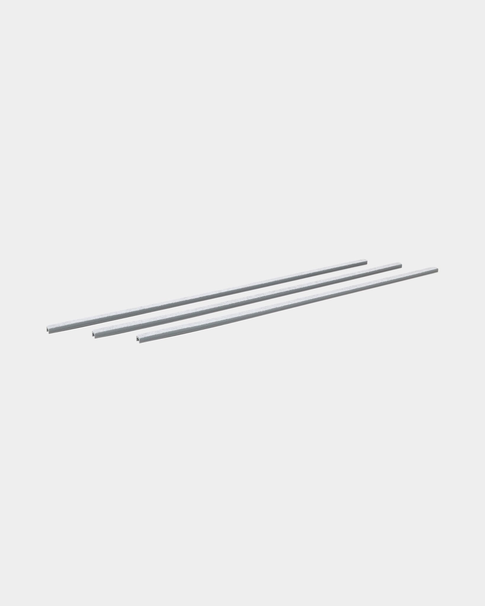 Tre grey Dupps Pop-on Cable Covers (3 pz) di WoodUpp sono allineati in parallelo, pensati per organizzare i cavi con i pannelli acustici in legno Akupanel.
