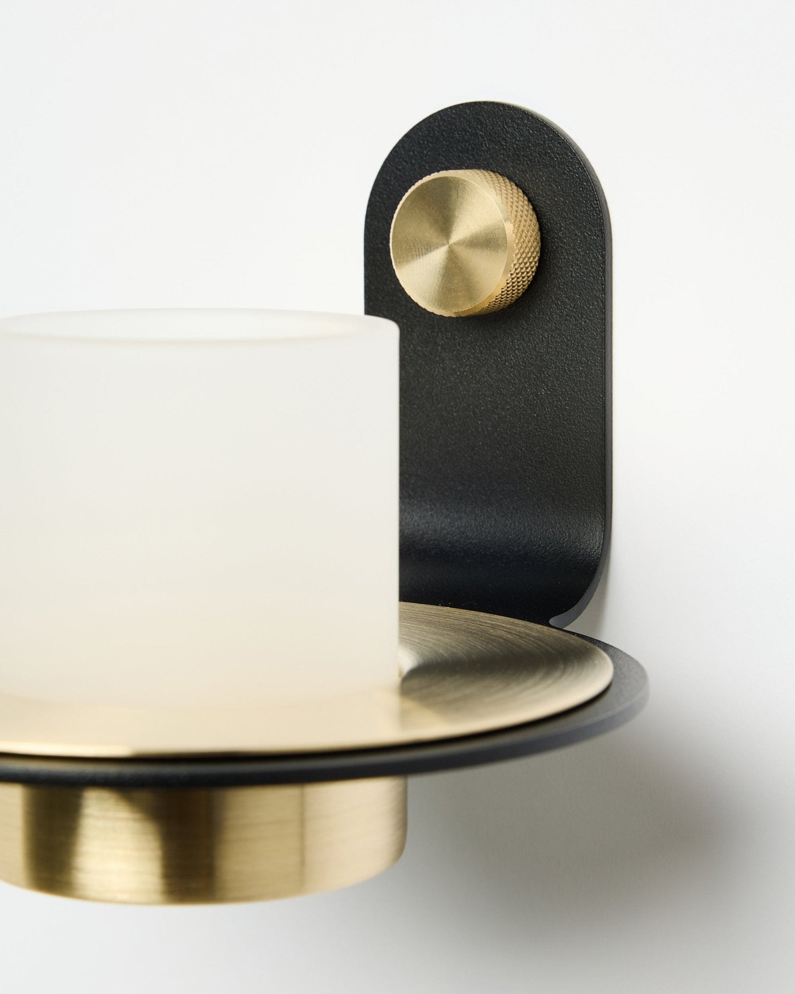 Il portacandela Norr di WoodUpp, in black e brass, mostrato montato con candele LED su un Pannello acustico bianco.