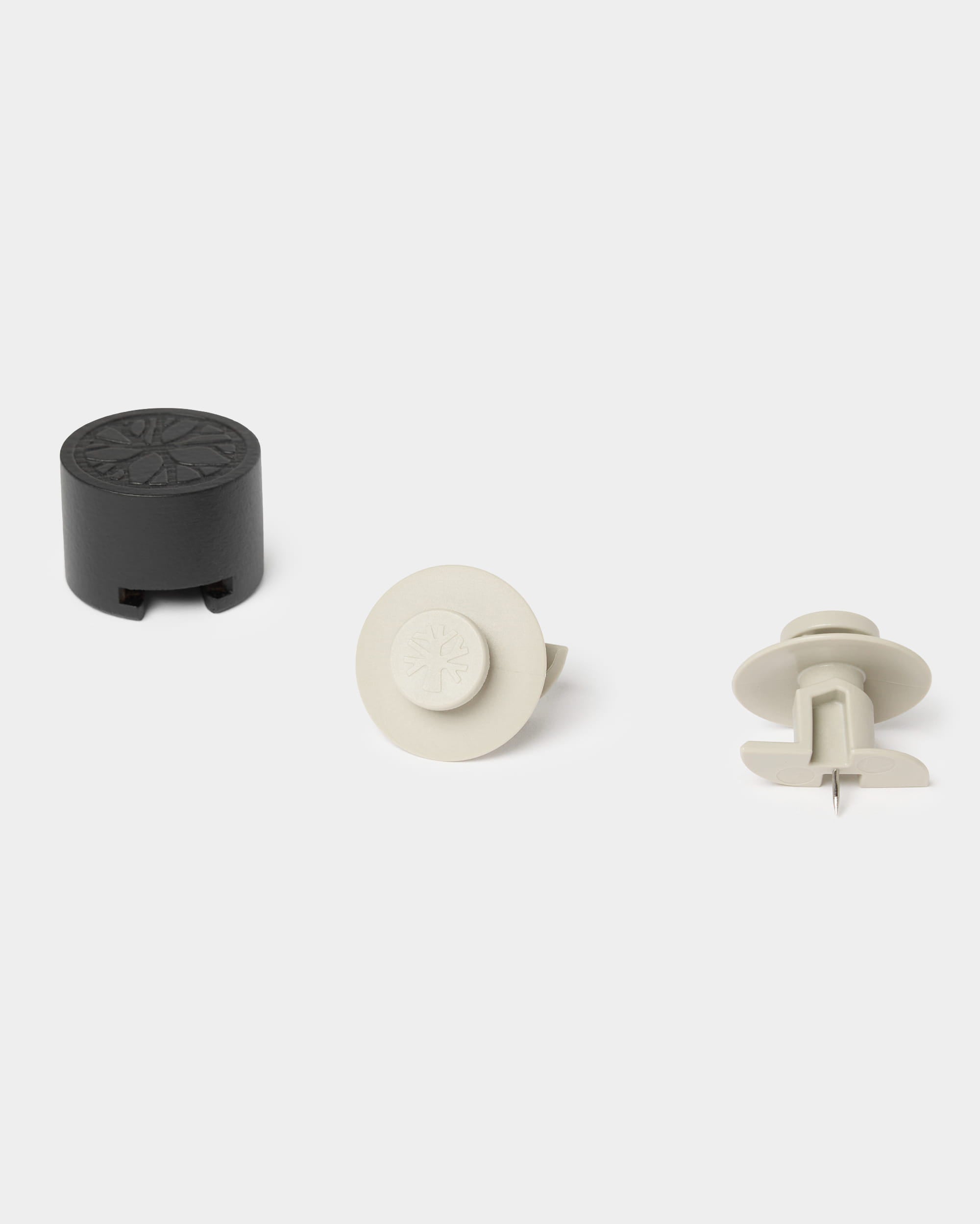 Sette ganci Dupps color beige e un attrezzo di montaggio WoodUpp disposti su una superficie chiara, progettati per il fissaggio dei pannelli acustici in legno Akupanel.