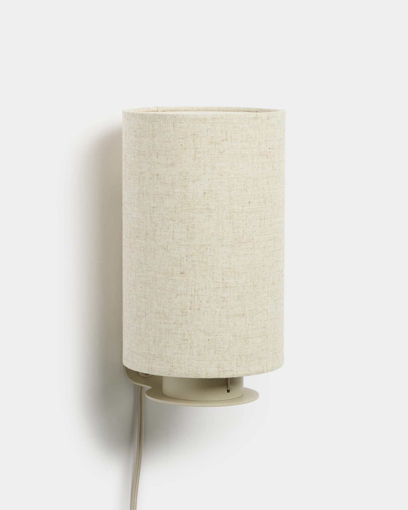 Feya | Wall Lamp di WoodUpp con paralume cilindrico in lino-cotone e cavo bianco a vista, finitura beige, progettata per abbinarsi ai pannelli acustici in legno.