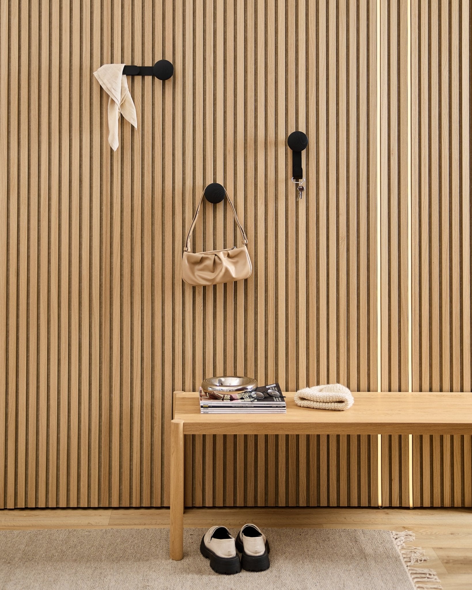 Ingresso minimalista con il gancio WoodUpp Linn Horizontal in Black Oak con ganci black, panca in legno, scarpe, libri e un piattino. Stile nordico.