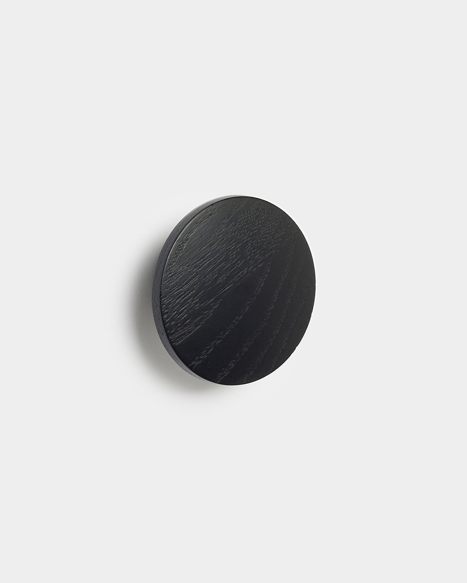 Il/la Linn | Single Hanger in black oak di WoodUpp, un accessorio rotondo per pannelli acustici Akupanel, mostrato su uno sfondo bianco uniforme.