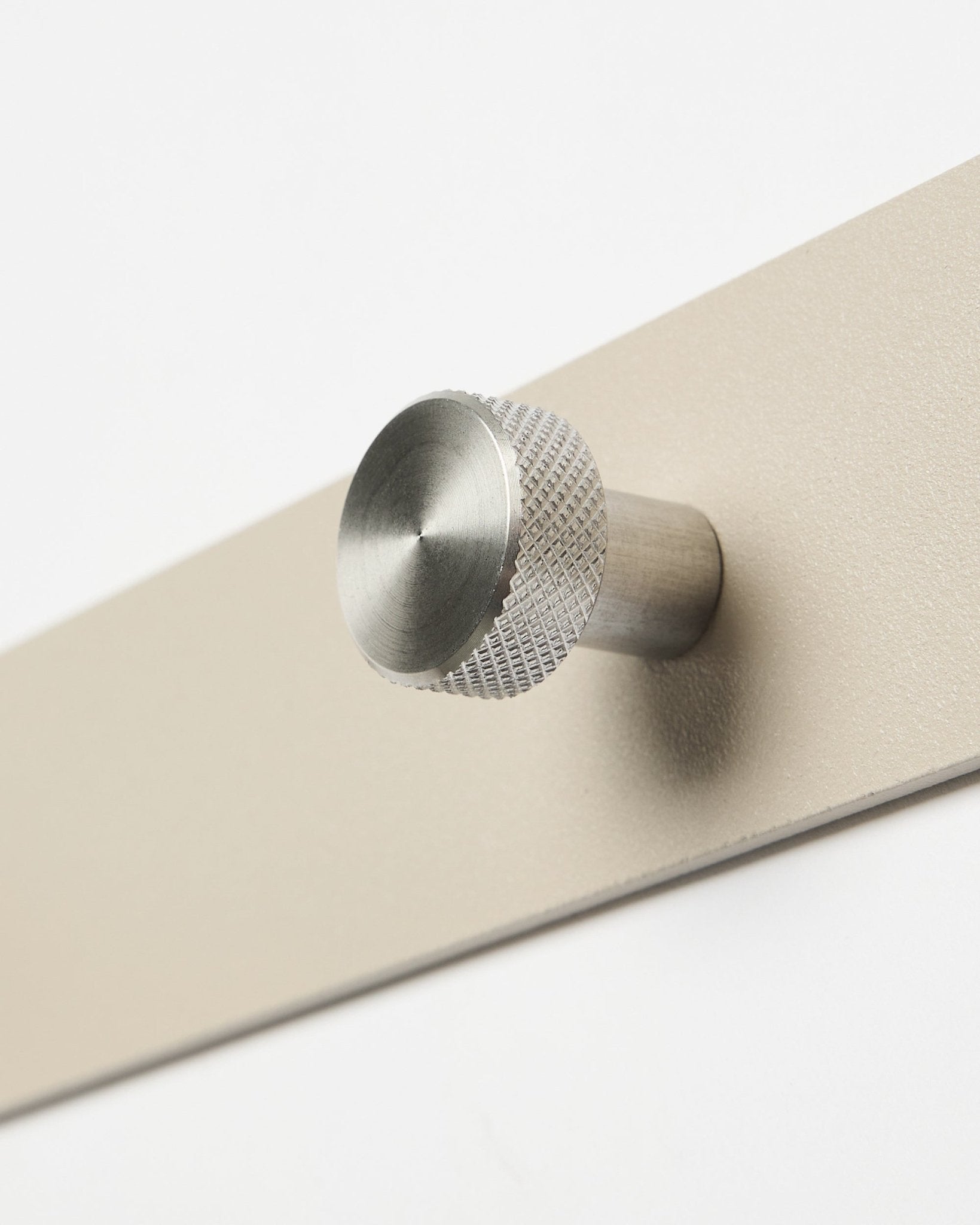Primo piano dell’appendiabiti a ganci WoodUpp Norr in beige e acciaio inox steel, X7, progettato come accessorio per i pannelli acustici in legno Akupanel o per organizzare l’ingresso.