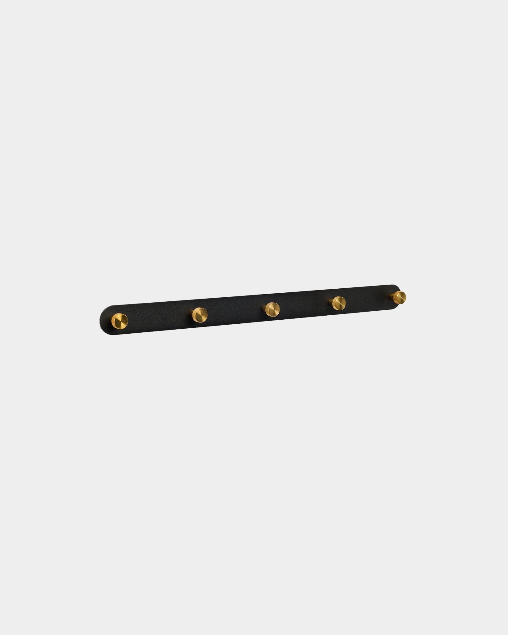 Appendiabiti WoodUpp Norr in black e brass con 5 ganci steel, montato a parete, mostrato su uno sfondo bianco semplice.