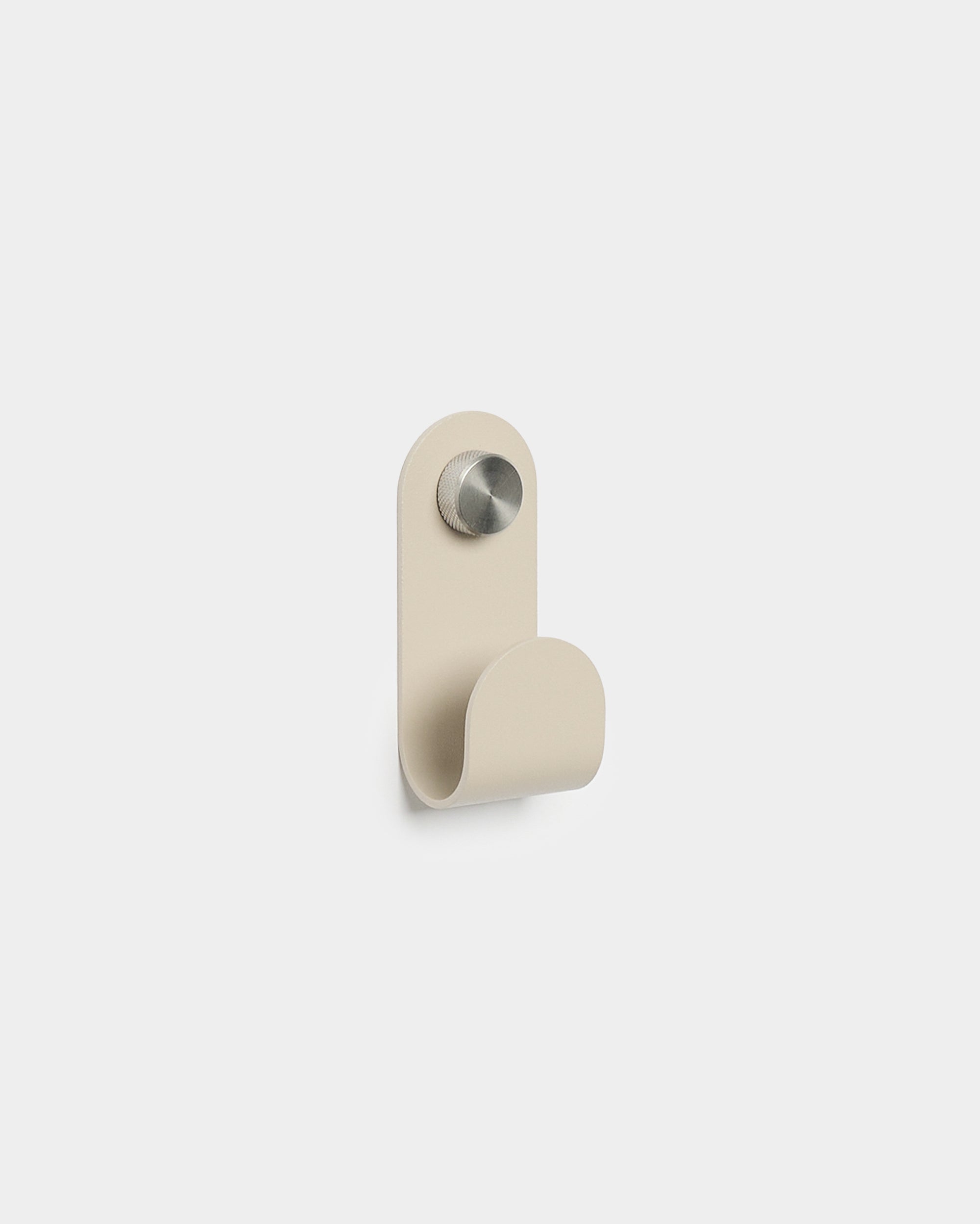 WoodUpp Norr Single Hanger in beige con una forma curva minimalista e finitura in metallo spazzolato, pensato come accessorio per ganci da parete Akupanel compatti.