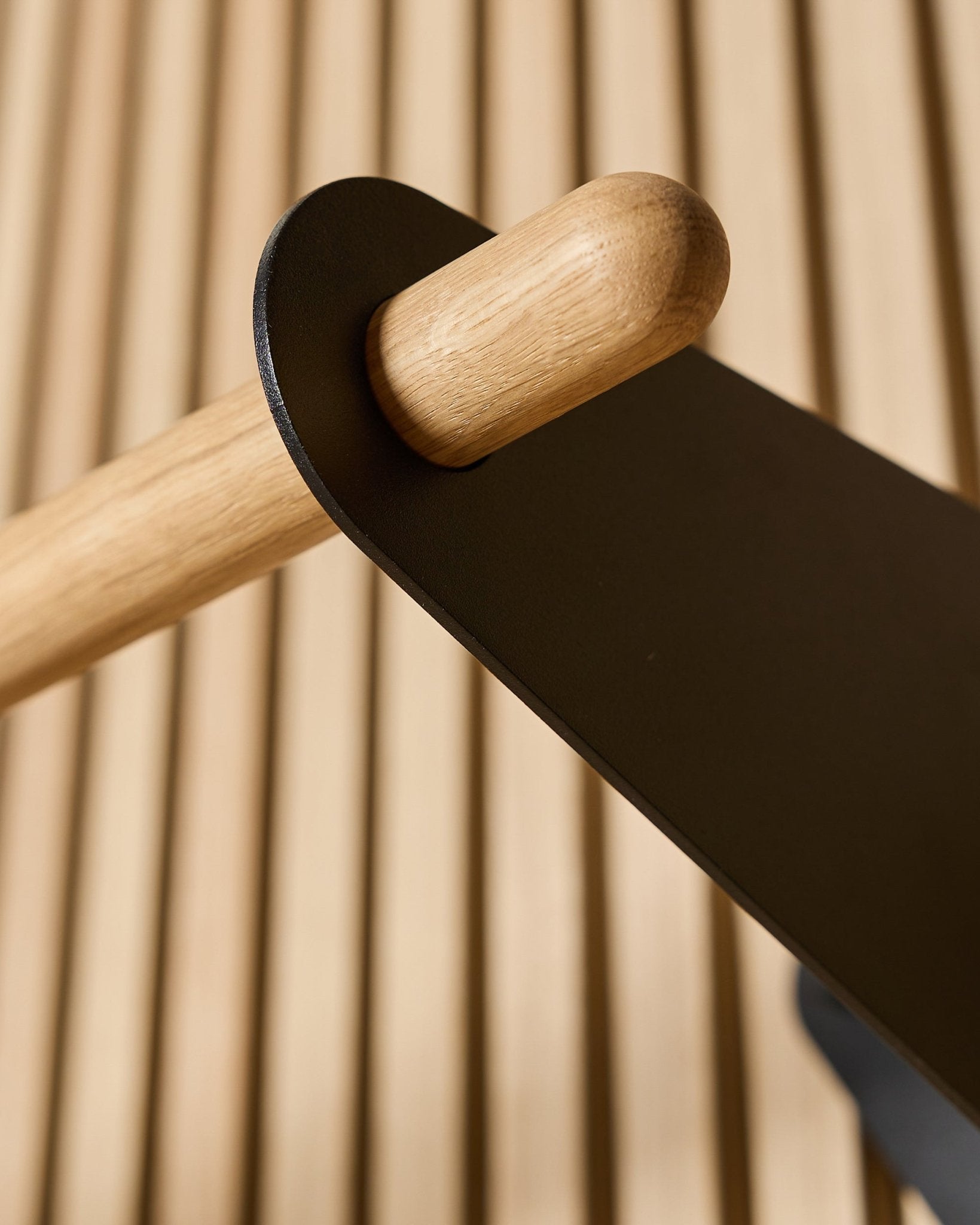 Primo piano del Coat Rail WoodUpp Linn in black, 75,9 cm, con un'asta piena Rovere montata su una staffa in metallo black su un pannello acustico a doghe Nordic.