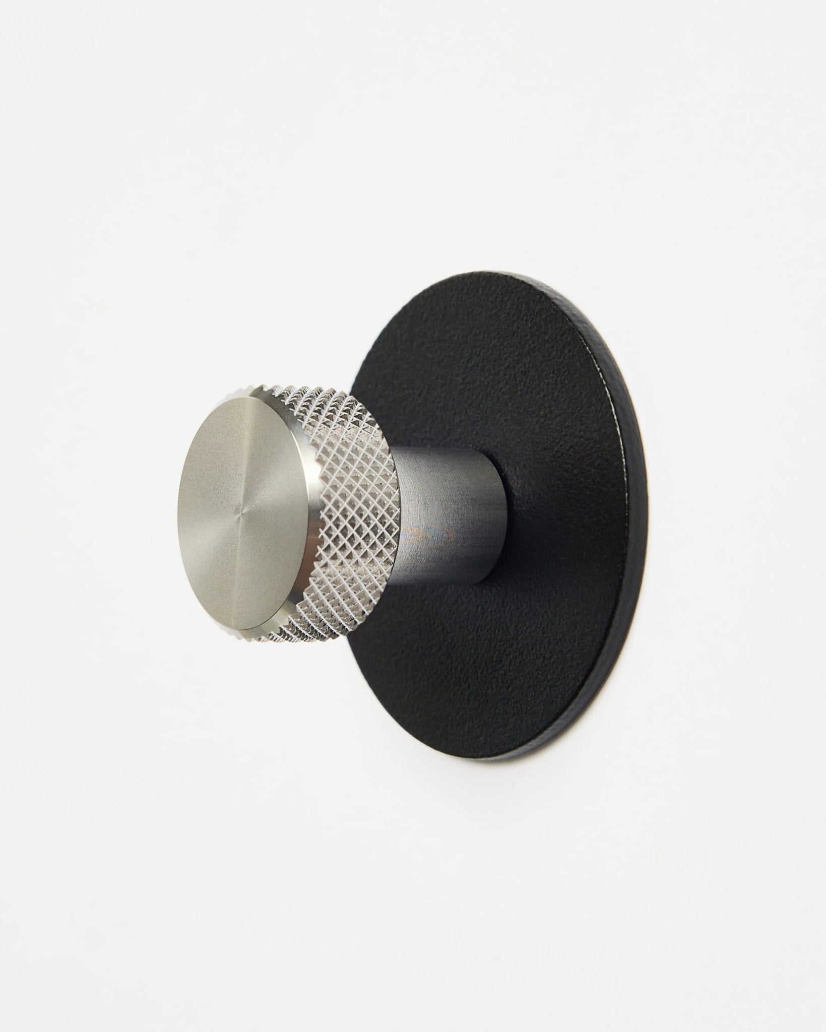 WoodUpp Norr | Coat Hook X1 in black e acciaio inox steel installato su una semplice parete bianca, progettato come accessorio della collezione CREATE per i sistemi Akupanel.